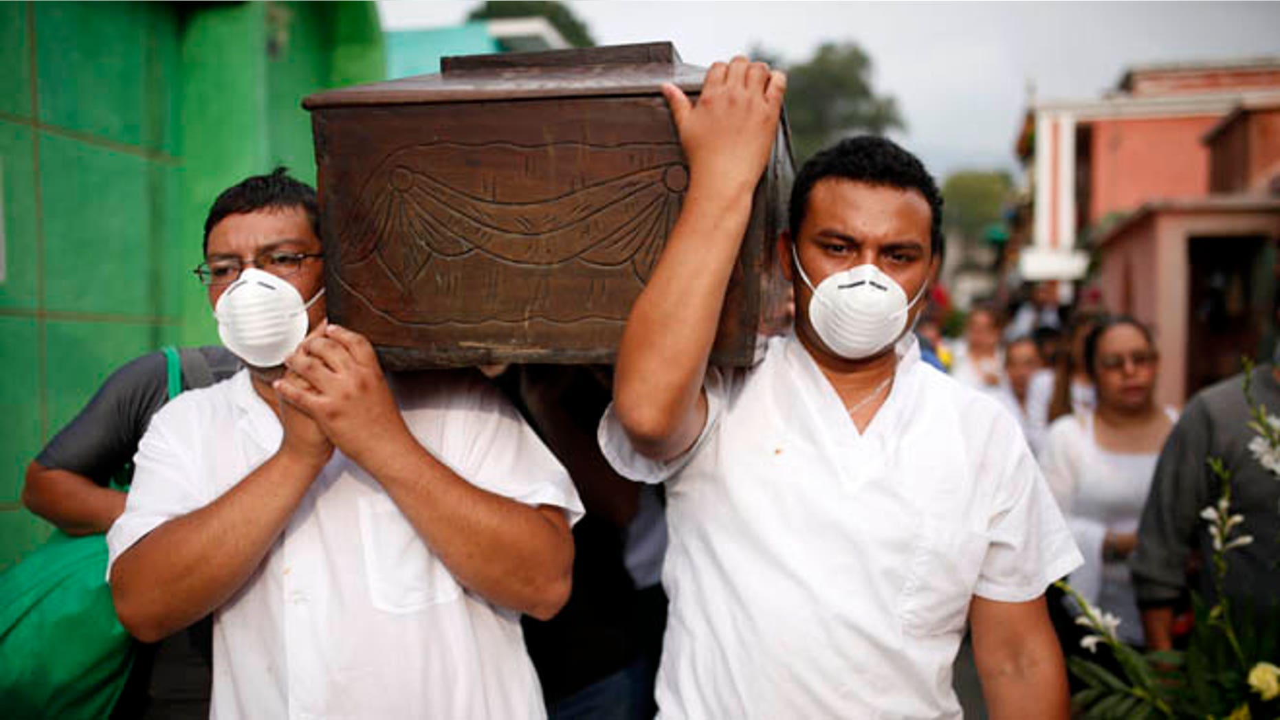 Men with their mouths covered wih surgical masks carry the coffin of a victim of the Cambray neighborhood mudslide, to the Santa Catarina Pinula cemetery on the outskirts of Guatemala City, Sunday, Oct. 4, 2015. Hope faded Sunday for finding any survivors of a mudslide that killed at least 87 people as authorities said that hundreds more may still be missing. (AP Photo/Luis Soto)