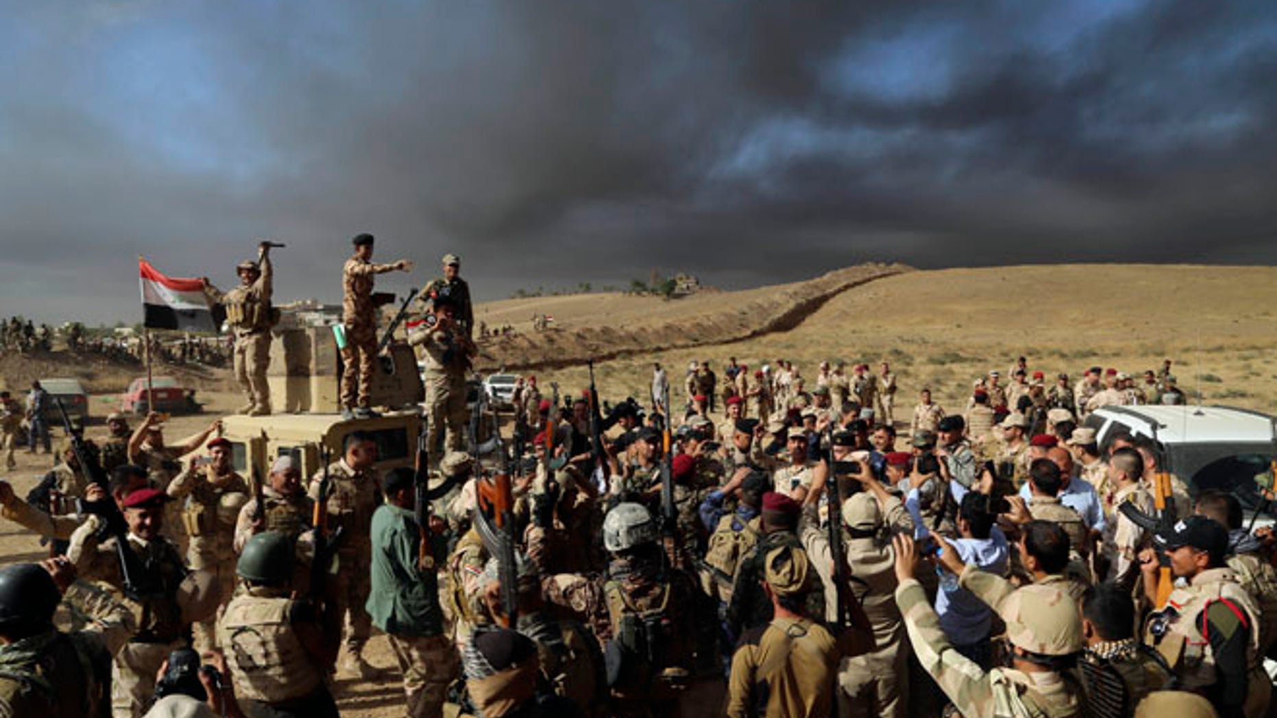OCT. 21: Iraqi Army soldiers raise their weapons in celebration on the outskirts of Mosul, Iraq