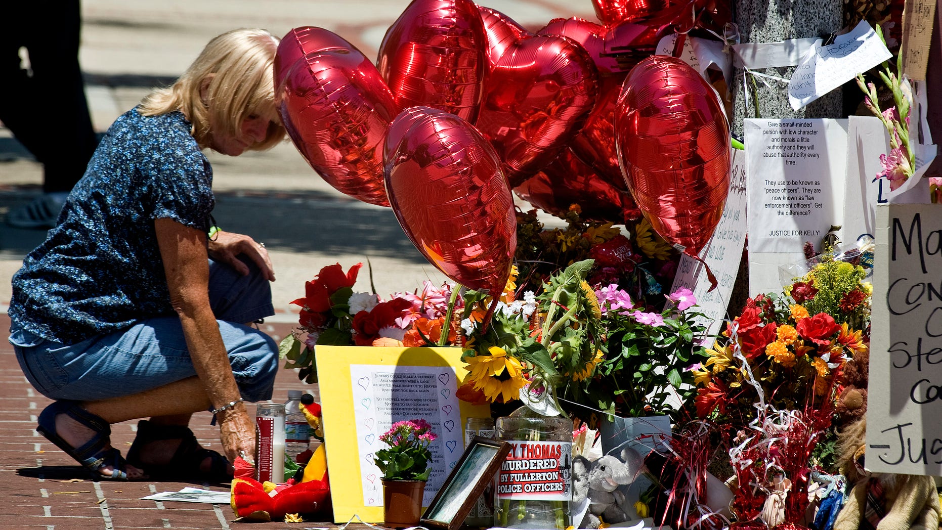 August 9: Cathy Thomas puts a candle blown over in the wind upright at the memorial that supporters have created near the spot where her son Kelly Thomas and police officers had their altercation in Fullerton, California. Kelly Thomas died at UCI Medical Center in Orange, five days after being involved in the physical confrontation with police.