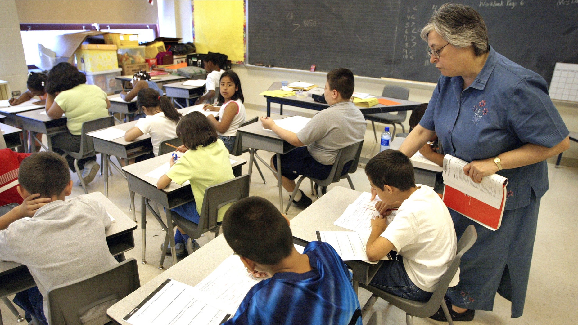 CHICAGO, IL - JULY 2: Teacher Arlene Lebowitz assists a student in her third-grade class during summer school July 2, 2003 in Chicago, Illinois. A record number of students are expected at summer school due to a strong showing for a new voluntary program for mid-tier students and strict application of non-ITBS (Iowa Tests of Basic Skills) test promotion standards. (Photo by Tim Boyle/Getty Images)