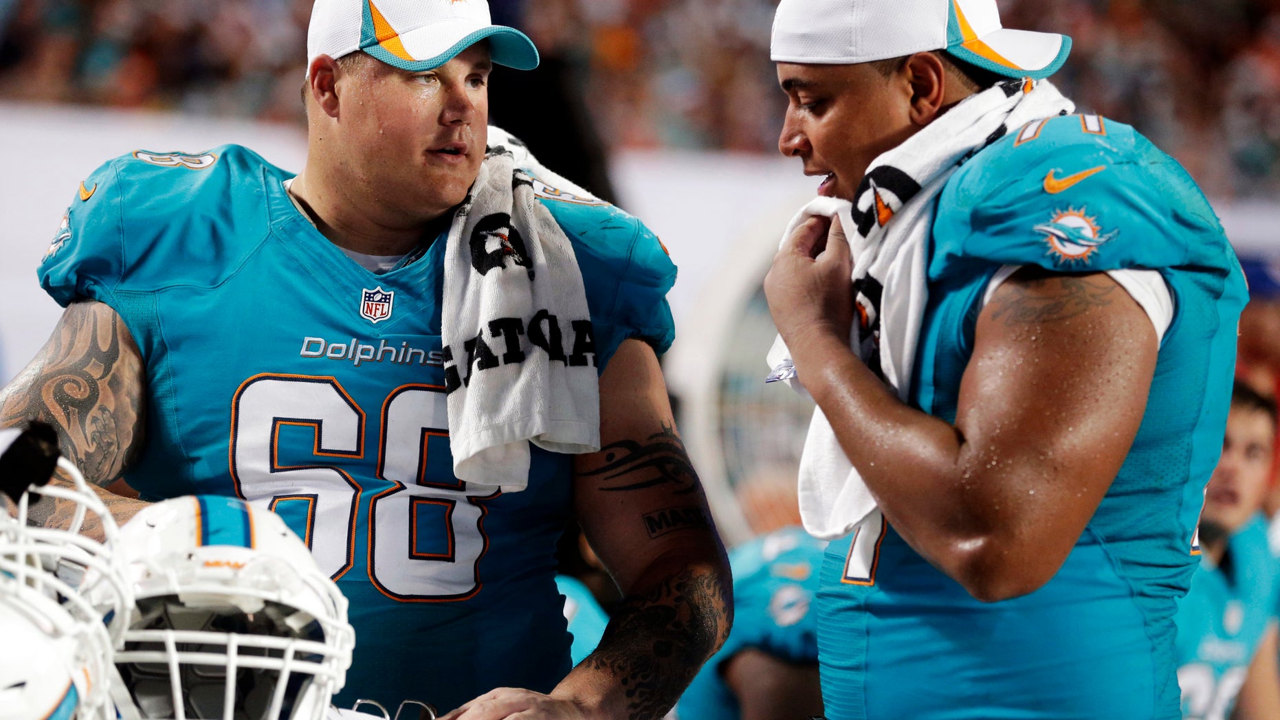 FILE - In this Aug. 24, 2013, file photo, Miami Dolphins guard Richie Incognito (68) and tackle Jonathan Martin (71) look over plays during an NFL preseason football game against the Tampa Bay Buccaneers in Miami Gardens, Fla. A report is expected soon from the NFL investigation into the Dolphins' harassment scandal involving Martin and Incognito. The Dolphins don't expect any major revelations, but neither player is likely to be back with the team next season. (AP Photo/Wilfredo Lee, File)