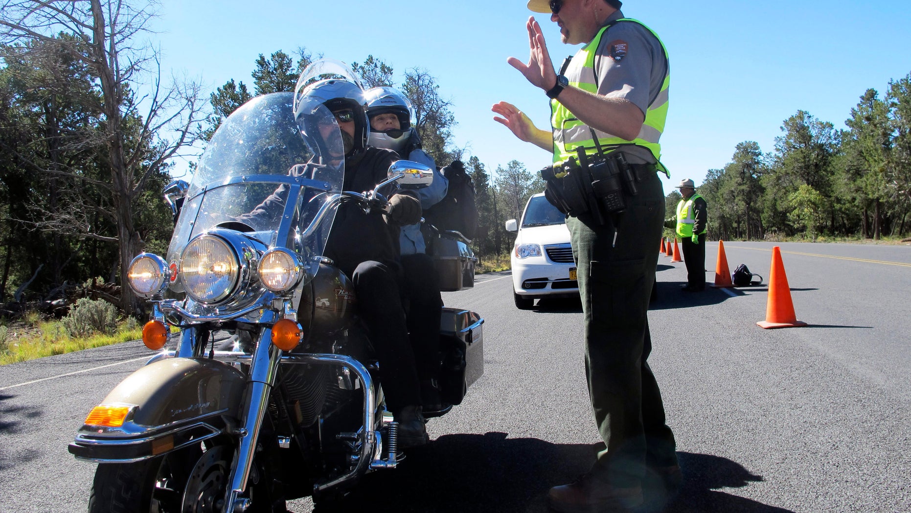 Grand Canyon National Park Ranger Jason Morris talks to people on a motorcycle at the closed park entrance on Thursday, Oct. 3, 2013 in Ariz. More than 400 national parks are closed as Congress remains deadlocked over federal government funding. (AP Photo/Brian Skoloff)