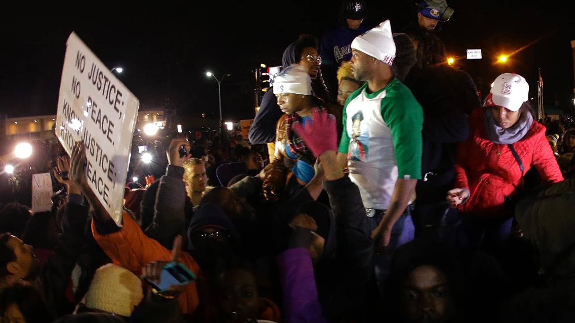 FILE - In this Nov. 24, 2014 file photo Louis Head, center right, Michael Brown's stepfather, and Brown's mother Lesley McSpadden, center left, react as they listen to the announcement that a grand jury decided not to indict Ferguson police officer Darren Wilson who fatally shot 18-year-old Brown. Brown has apologized for angry comments he made after the decision was announced, but said his remarks had nothing to do with the arson and looting that ravaged Ferguson and the surrounding area. (AP Photo/Charlie Riedel, File)
