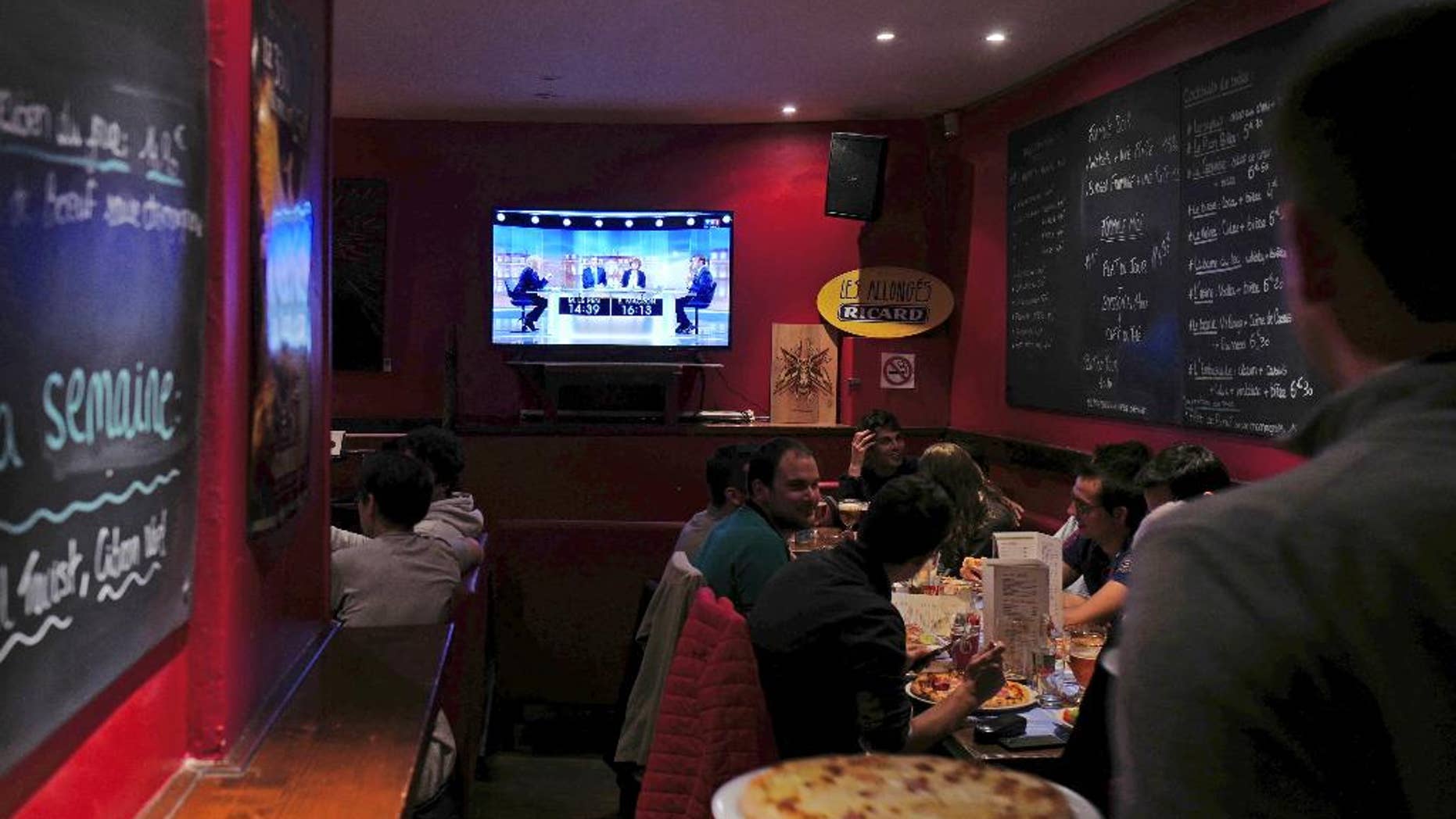 People watch a live broadcast television debate with French centrist presidential candidate Emmanuel Macron, right, and far-right candidate Marine Le Pen, in a restaurant in Lille, northern France, Wednesday, May 3, 2017. Le Pen and Emmanuel Macron exchanged barbs and insults on Wednesday during their sole televised debate ahead of Sunday's runoff election. (AP Photo/Michel Spingler)