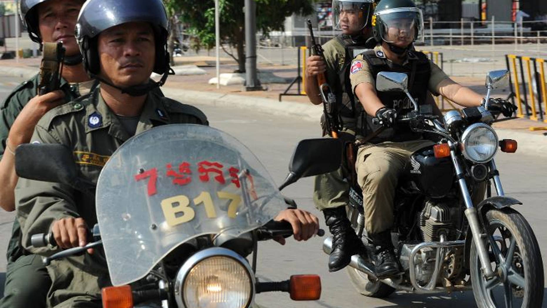 Cambodian police officials ride their motorbikes in Phnom Penh on March 21, 2012