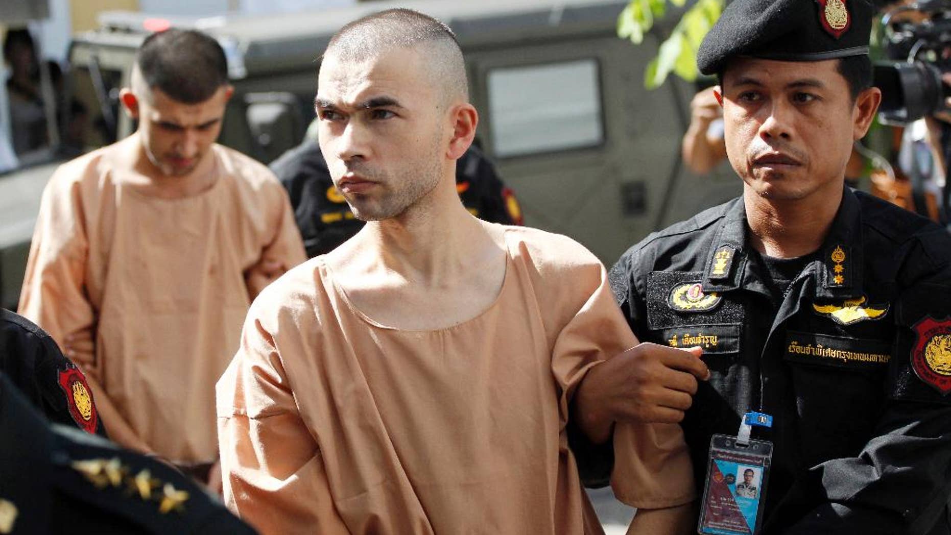FILE - In this Nov. 24, 2015 file photo, police officers escort suspects in the Aug. 17 blast at Erawan Shrine, Bilal Mohammad, front, and Mieraili Yusufu, rear, as they arrive at a military court in Bangkok, Thailand. Testimony begun Tuesday, Nov. 15, 2016 in the trial of two men accused of the deadly 2015 bombing at a Bangkok landmark after a dispute over the defendants' translators. (AP Photo/Sakchai Lalit, File)