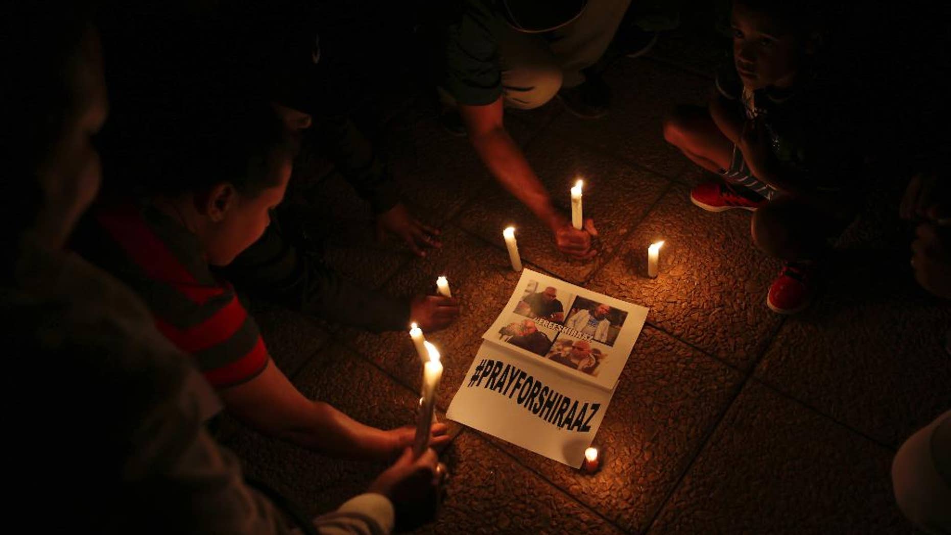 South Africans light candles during a vigil held in Johannesburg Wednesday, Jan. 18, 2017, for South African freelance photographer Shiraaz Mohamed who was abducted in Syria last week. People prayed and held signs calling for the safe return of Mohamed who was kidnapped on Jan. 10, while traveling with aid workers to Syria's border with Turkey. (AP Photo/Denis Farrell)