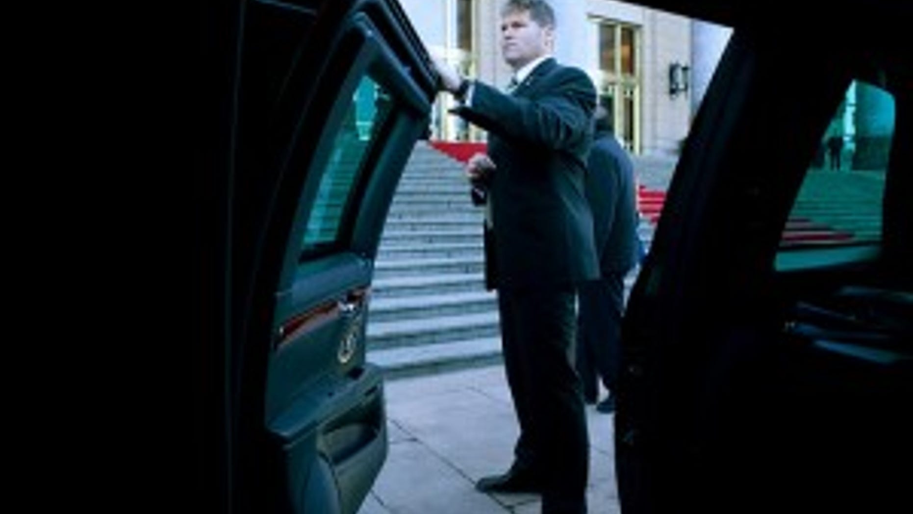 A U.S. Secret Service agent waits by the spare limousine before President Barack Obama's motorcade departs for a tour of the Forbidden City in Beijing, China, Nov. 17, 2009. (Official White House Photo by Pete Souza) **Note the size of the door!