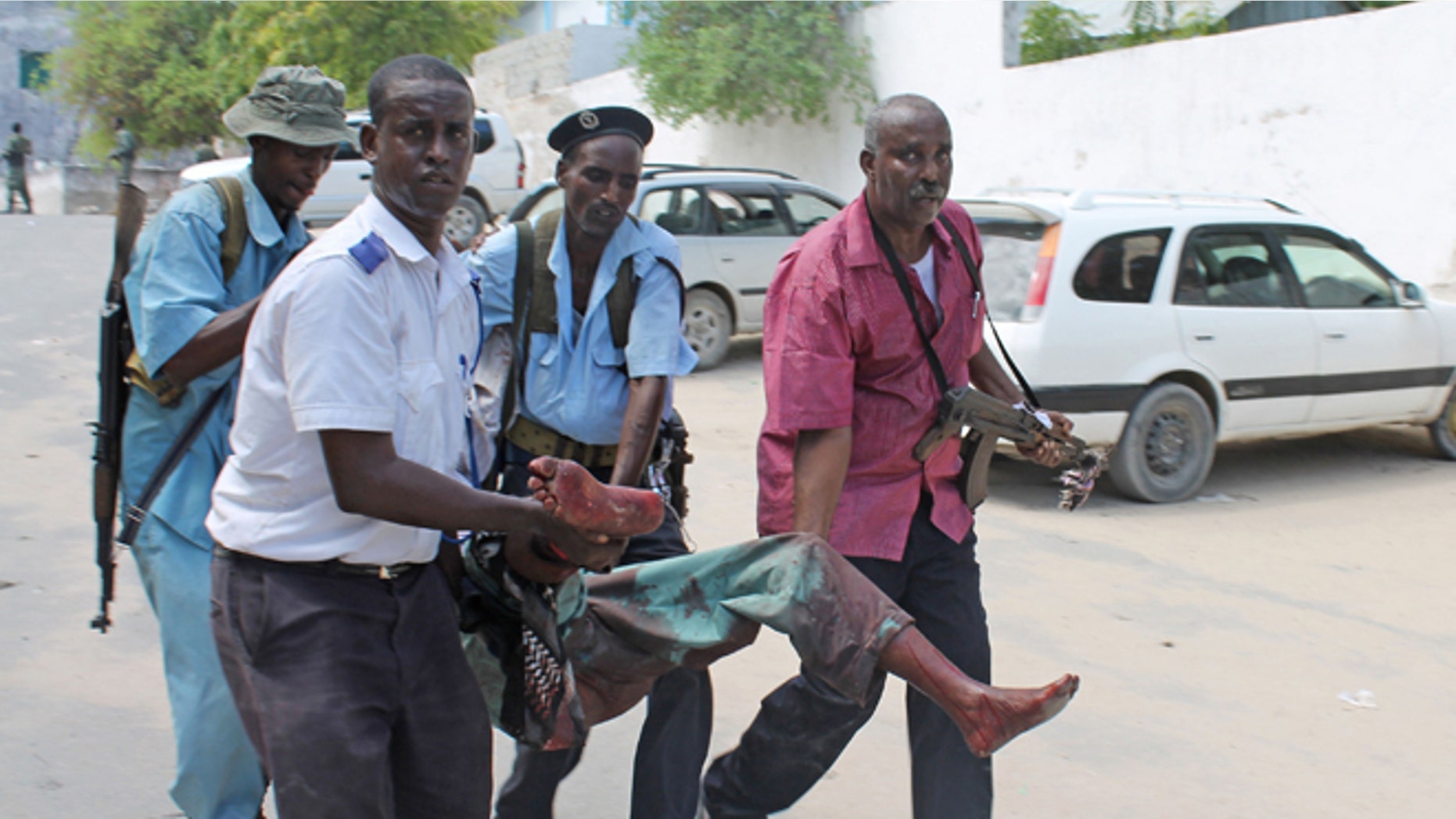 Somali soldiers carry a wounded civilian from the entrance of Mogadishus court complex after being injured during a siege by militants, in Mogadishu, Somalia, Sunday, April 14, 2013. (AP)