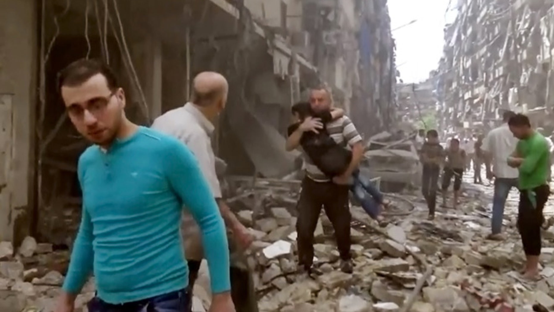 April 28, 2016 image made from video and posted online from Validated UGC, a man carries a child after airstrikes hit Aleppo, Syria.