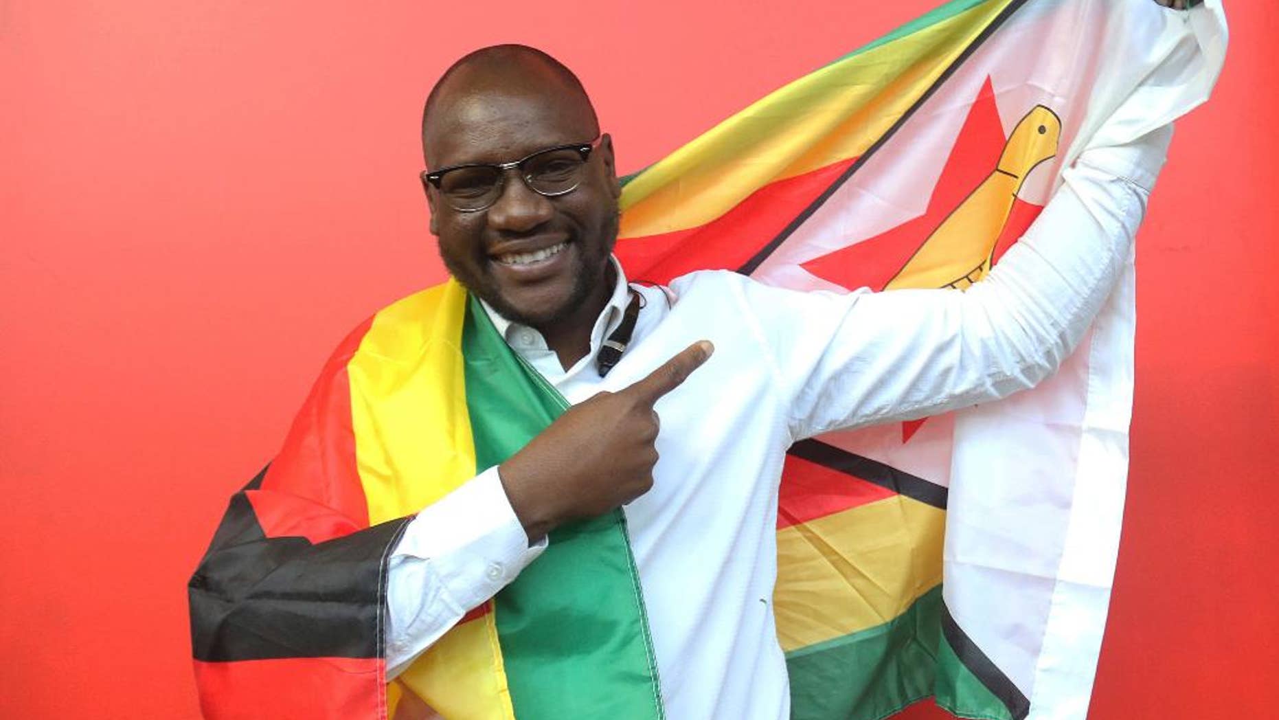 FILE - In this Tuesday May. 3, 2016 file photo, Evans Mawarire a young pastor in the Harare poses for a photo with the Zimbabwean flag wrapped around his body. A lawyer says a Zimbabwe pastor who fled to the United States after launching a popular protest movement has been arrested on his return home. Lawyer Harrison Nkomo says Evan Mawarire was picked up at Harare International Airport on Wednesday, Feb. 1, 2017. (AP Photo/Tsvangirayi Mukwazhi, File)
