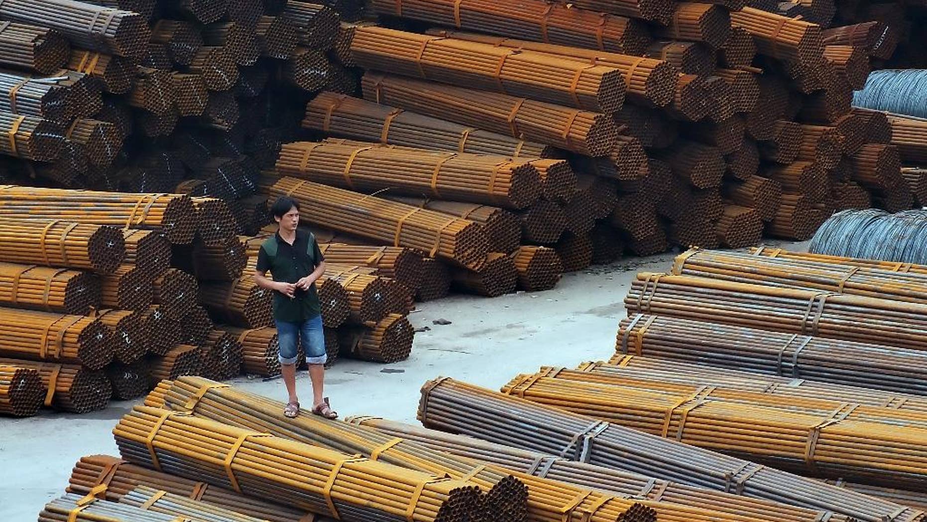 In this Aug. 22, 2014 photo, a man stands on bundles of steel pipes in a steel products dockyard along the Yangtze River in southwestern China's Chongqing Municipality. Regulators told Chinese banks on Thursday, April 21, 2016, to finance steel exports to help reduce a supply glut in a move that could worsen trade tensions with Europe and the United States. (Chinatopix via AP) CHINA OUT
