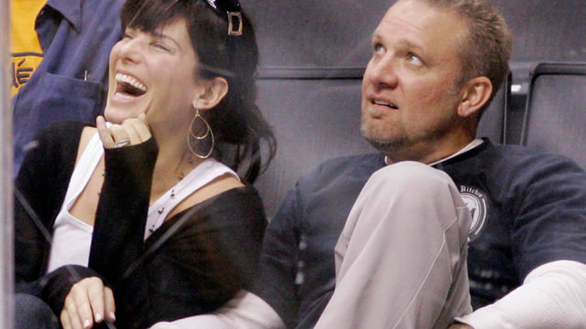 **FILE** Actress Sandra Bullock laughs as she watches the video board with her husband Jesse James during the Los Angeles Kings' NHL hockey game against the Anaheim Ducks, in this Oct. 22, 2006 file photo in Los Angeles. Before she got to know him, Bullock says she tagged her husband as a brutish "bigot." (AP Photo/Mark J. Terrill, file)