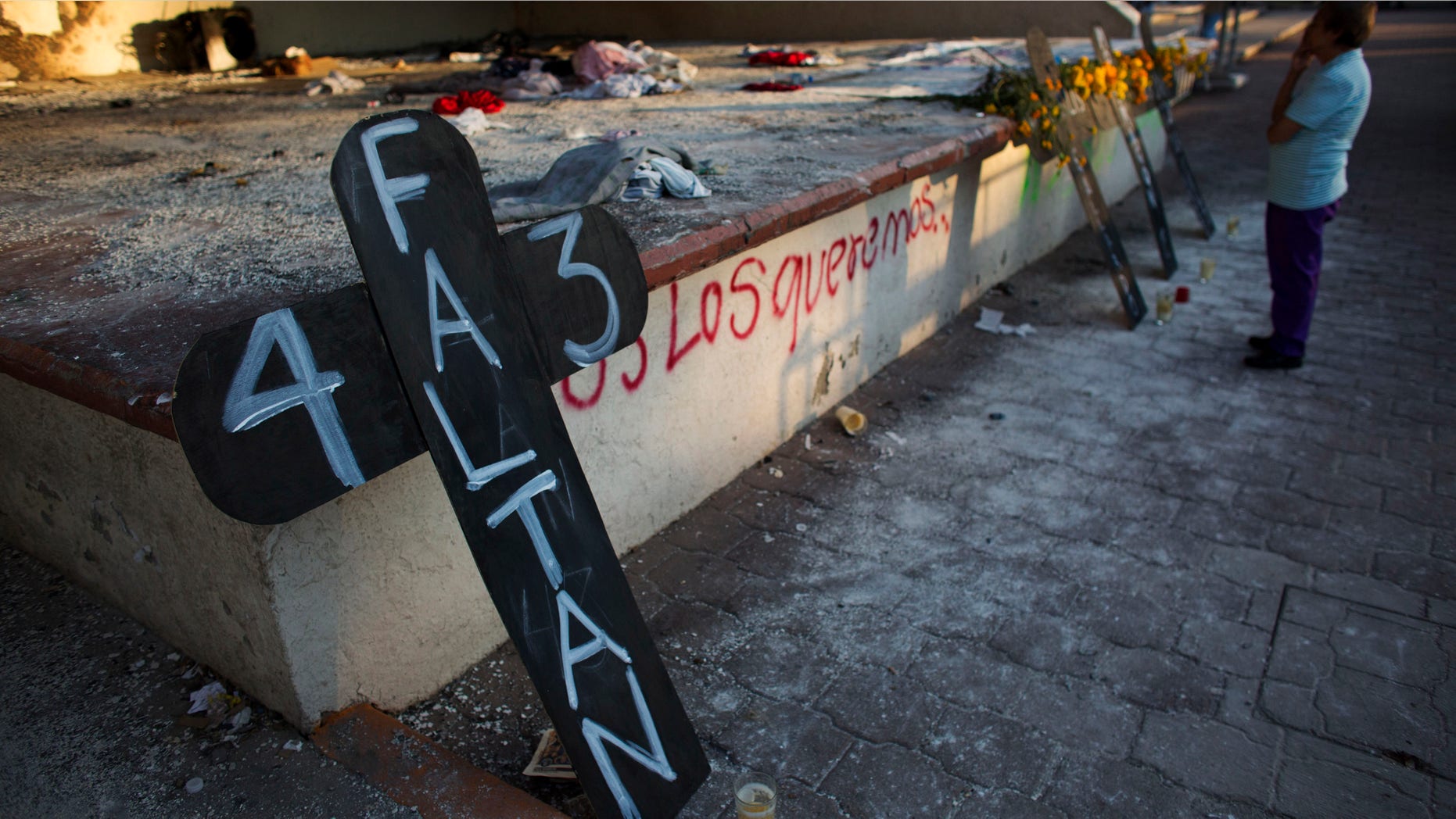 FILE - In this Oct. 28, 2014, file photo, a local resident pauses to contemplate crosses set to remember 43 missing students, in front of the burnt town hall, in Iguala, Mexico. Argentine forensics experts on Saturday Feb. 7, 2015, questioned Mexicoâs investigation into the disappearance of 43 students, saying the evidence doesnât support the governmentâs conclusion the youths were killed and burned to ashes. (AP Photo/Rebecca Blackwell, File)