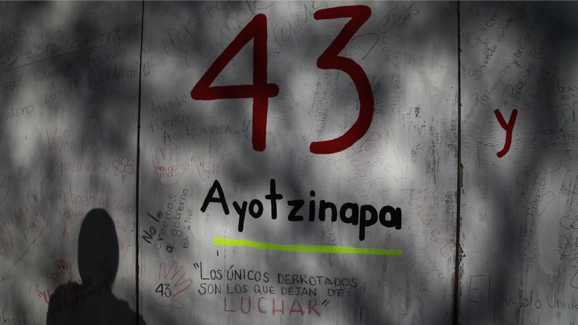 FILE - In this Dec. 28, 2014 file photo, the shadow of a demonstrator is cast on a wall with graffiti protesting the disappearance of 43 rural college students, in front of the Mexican Attorney General's office, in Mexico City. Mexican prosecutors said Tuesday, Jan. 20, 2015, that an Austrian forensics lab has been unable to find any more DNA that could be used by conventional means to identify charred remains that might be those of missing college students, but said they have authorized a final, unconventional effort. (AP Photo/Marco Ugarte, File)
