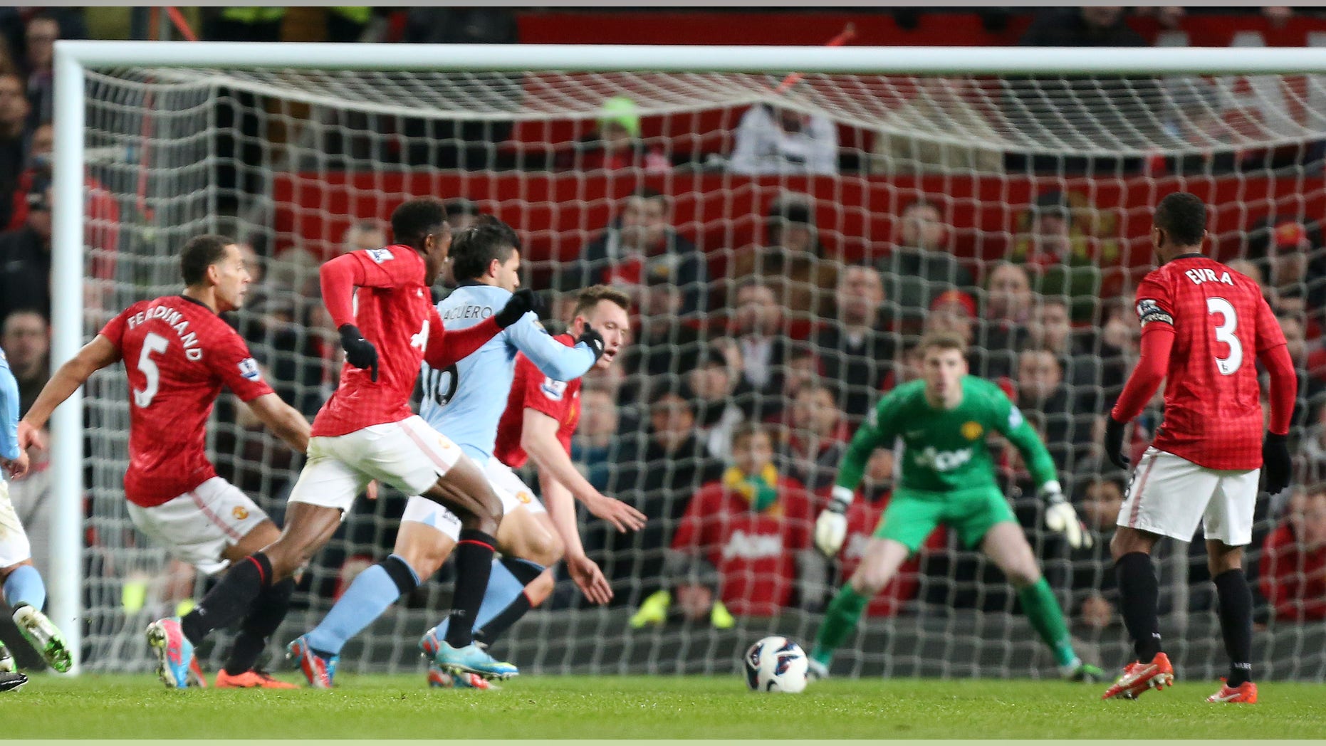 Sergio Agüero, en azul, se abre paso para anotar un gol para el Manchester City ante Manchester United el lunes 8 de abril de 2013. (AP Foto/Jon Super)