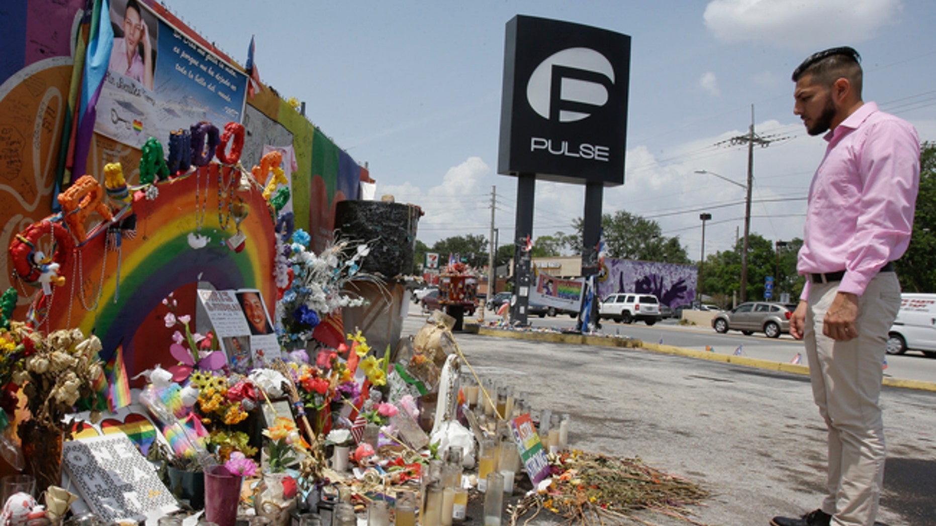 In this Tuesday, May 30, 2017 photo, Marco Quiroga, who works to support LGBTQ and social-justice causes in central Florida, reflects in front of one of the memorials at the Pulse Nightclub in Orlando, Fla. A year after the Pulse Nightclub shooting, the city's gay Latinos are trying to build up their community by forming support groups, seeking seats at the tables of power and creating a foundation to champion gays and Latinos. (AP Photo/John Raoux)