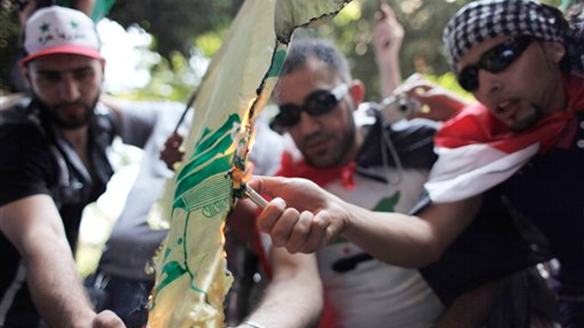 Protesters set fire to a Hezbollah flag, during an anti-Syrian regime rally near the Syrian embassy in Cairo, Egypt. Syrian troops fired Tuesday on residents who set up makeshift roadblocks to prevent the advance of tanks ringing the city of Hama, which has become a flashpoint of the uprising against autocratic President Bashar Assad, activists said.