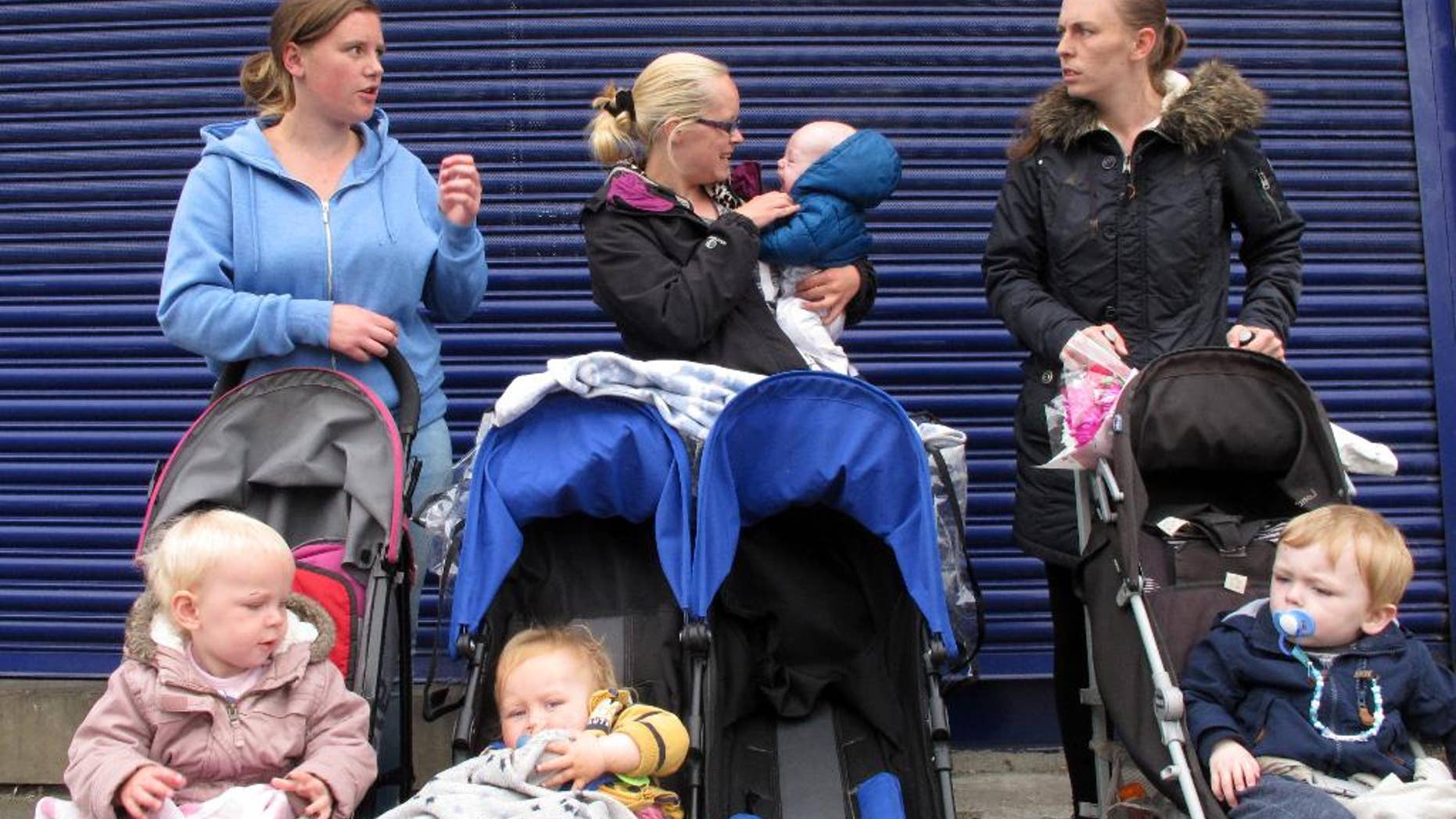 Keira Firth, left, Jessica Clarkson, center, and Jodie Britton stand with their children for the photographer in Birstall, England, Saturday June 18, 2016, after laying floral tributes for Jo Cox, the 41-year-old British Member of Parliament shot and stabbed to death Thursday. Both Britton and her friend, Jessica Clarkson, had come to pay respects to Cox after both received help from the lawmaker in fixing problems with their state-provided homes. (AP Photo/Shawn Pogatchnik)