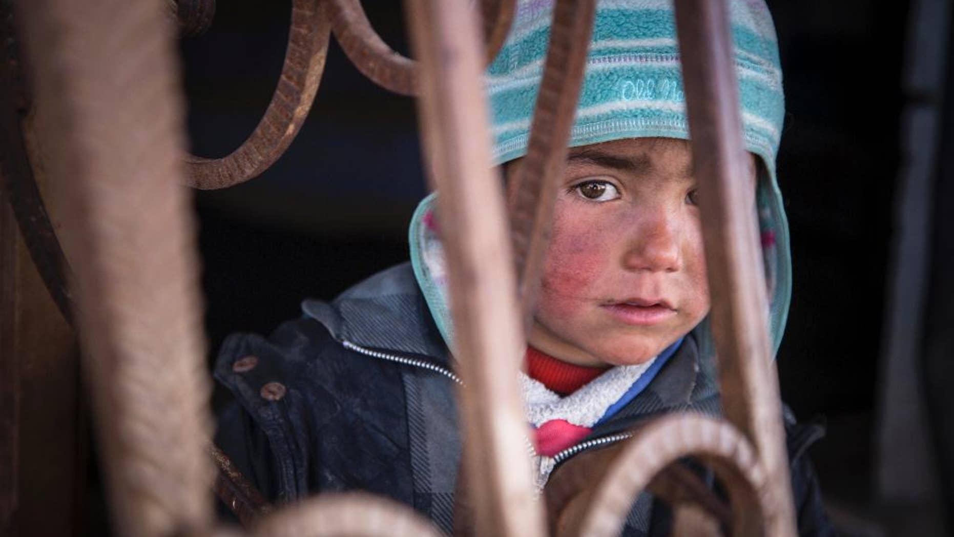 In this picture taken, Feb. 16, 2017, a child looks out from an abandoned petrol station where he and his family now live. The petrol station, badly damaged by war, is now the home of five families who have returned to Tel Abiad district, Raqqa Governorate, Syria, after fleeing from ISIS two years earlier only to find their homes destroyed. A new report by Save the Children says Syrian children are showing symptoms of ‘toxic stress’ from war exposure, and attempting self-harm and suicide. (Photo Courtesy: Jonathan Hyams, Save the Children via AP)