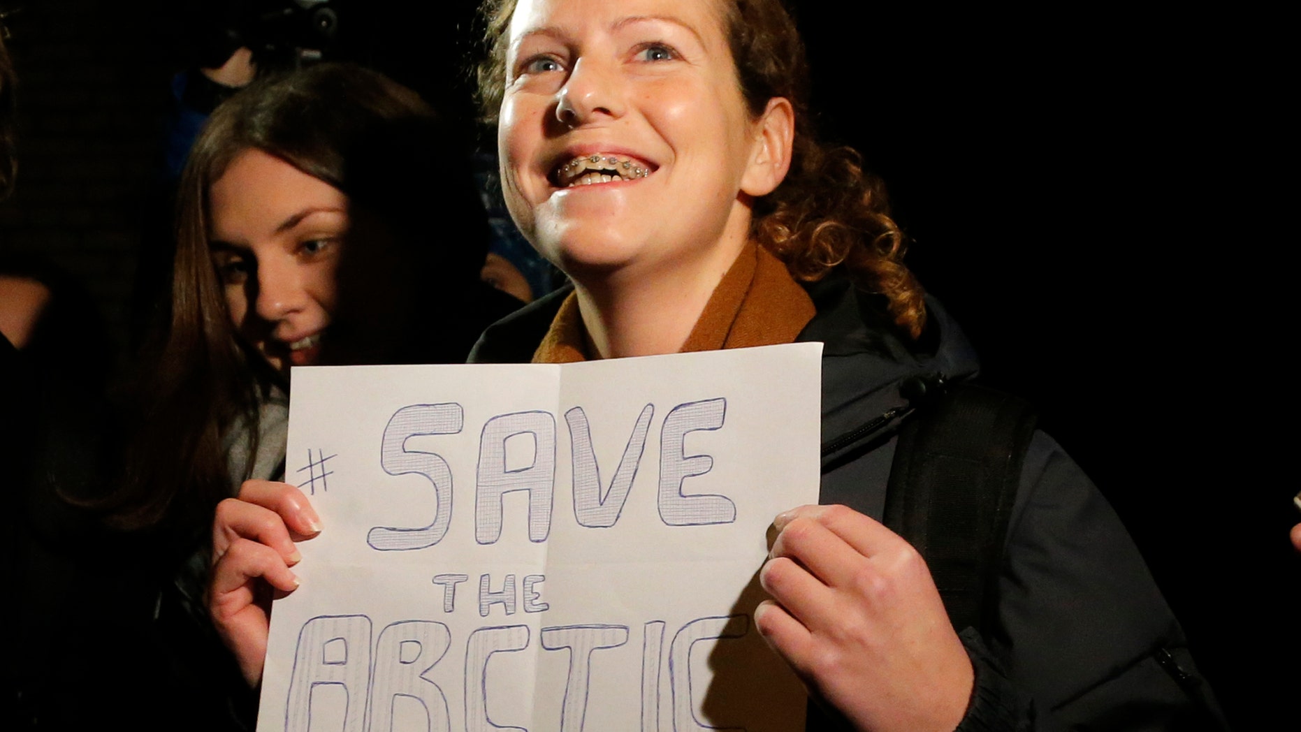 Greenpeace International activist Ana Paula Alminhana Maciel of Brazil holds a poster as she is released from jail on bail in St. Petersburg, Russia, Wednesday, Nov. 20, 2013. Russian courts granted bail Wednesday to the American captain and four others arrested on a Greenpeace ship over a protest against oil drilling in the Arctic. They are among 30 people detained in the case. (AP Photo/Dmitry Lovetsky)