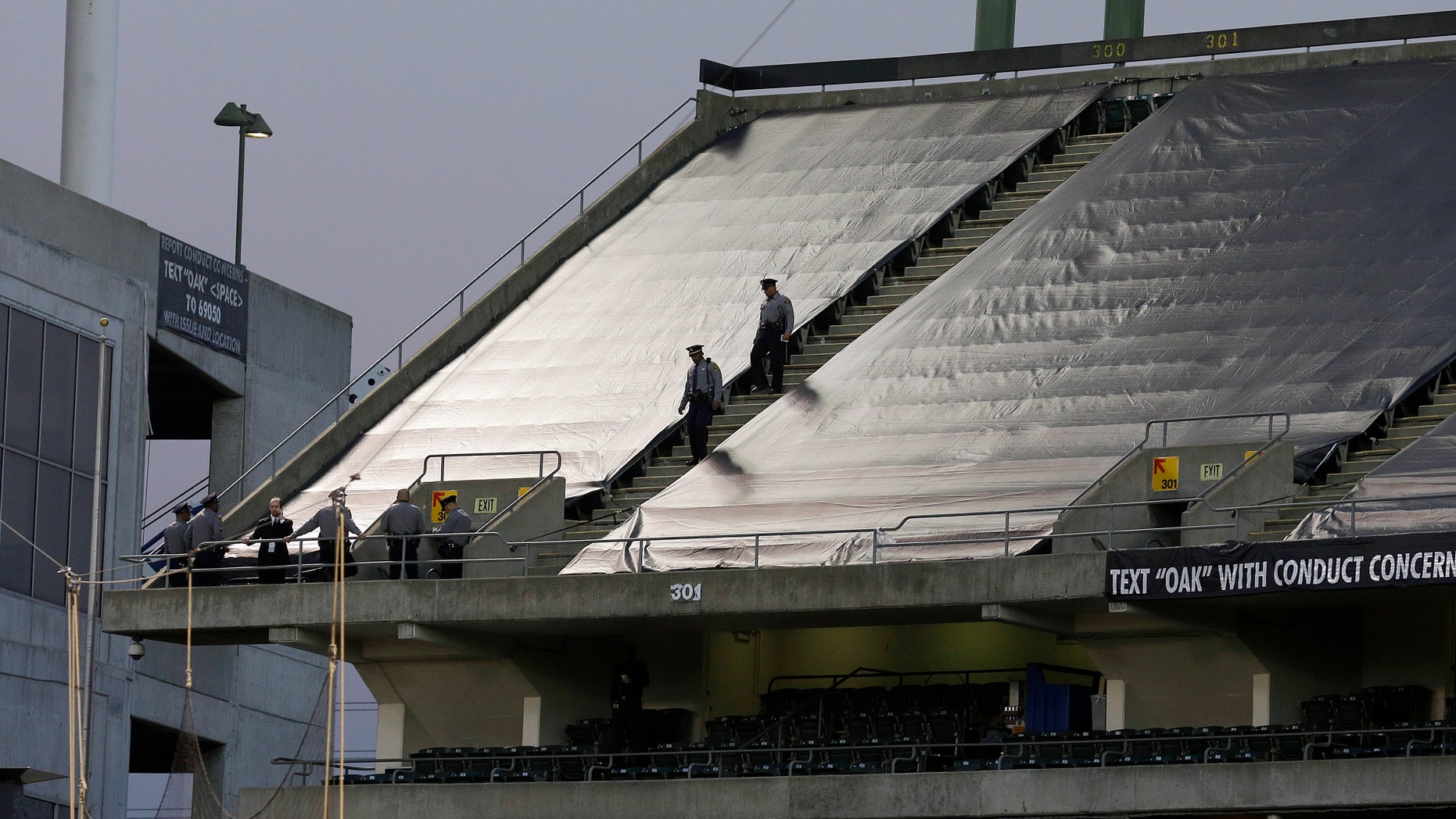 Law enforcement officials walk in the upper deck of O.co Coliseum after an NFL football game between the Oakland Raiders and the Tennessee Titans in Oakland, Calif., Sunday, Nov. 24, 2013. Authorities say a football fan jumped after the game from the third deck of the Oakland Coliseum, injuring herself and a man one level below who tried to catch her. She and the man who tried to catch her were rushed to the hospital for treatment. (AP Photo/Jeff Chiu)