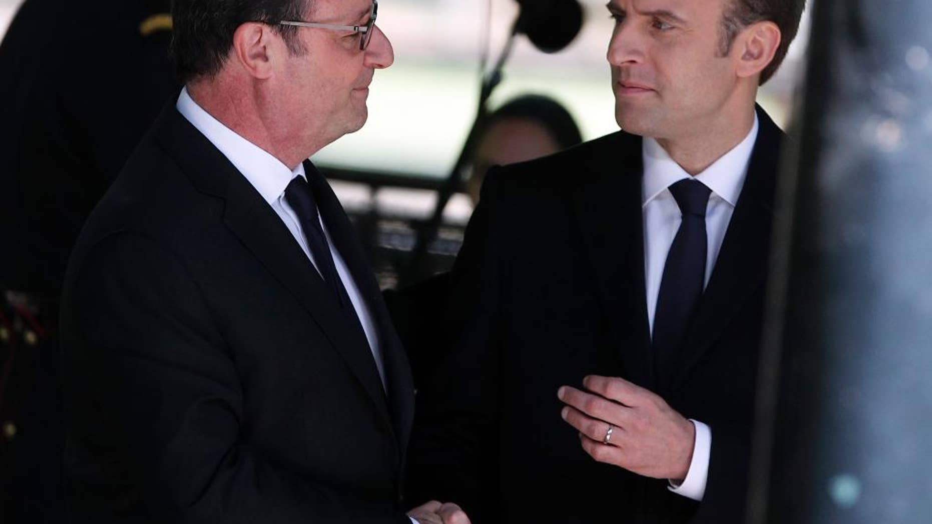 Outgoing French President Francois Hollande, left, and French President-elect Emmanuel Macron shake hands as they attend a ceremony commemorating the abolition of slavery, in Paris, Wednesday, May 10, 2017. (AP Photo/Christophe Ena)