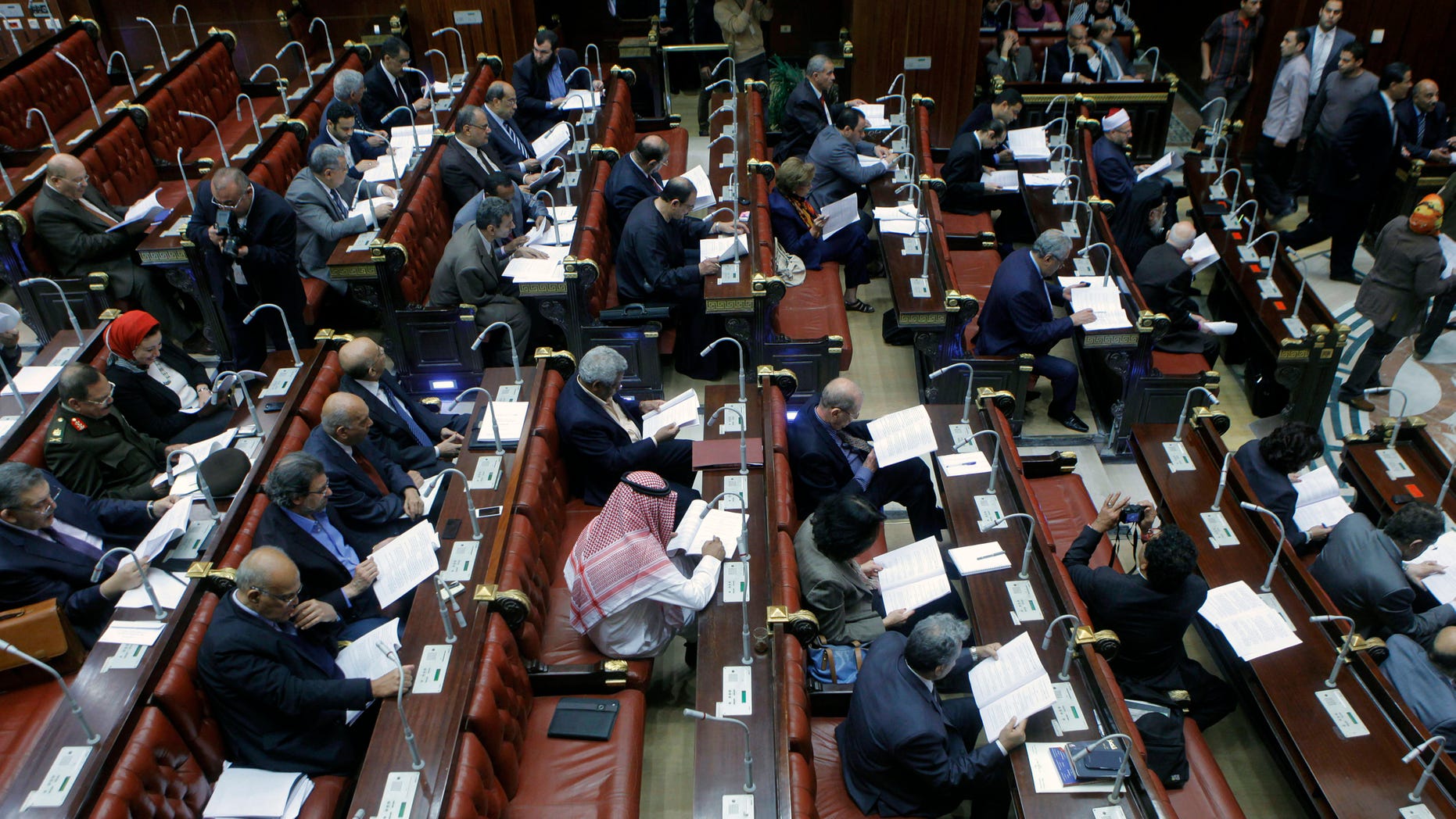 Members of Egypt's panel tasked with amending Egypt's Islamist-drafted constitution, read drafts of the constitution before they begin voting on a series of amendments, in the Shoura Council, Cairo, Egypt, Saturday, Nov. 30, 2013. The 50-member committee will hand in the draft constitution to interim Egyptian President Adly Mansour, who has a month to call for a public vote on it. (AP Photo/Amr Nabil)