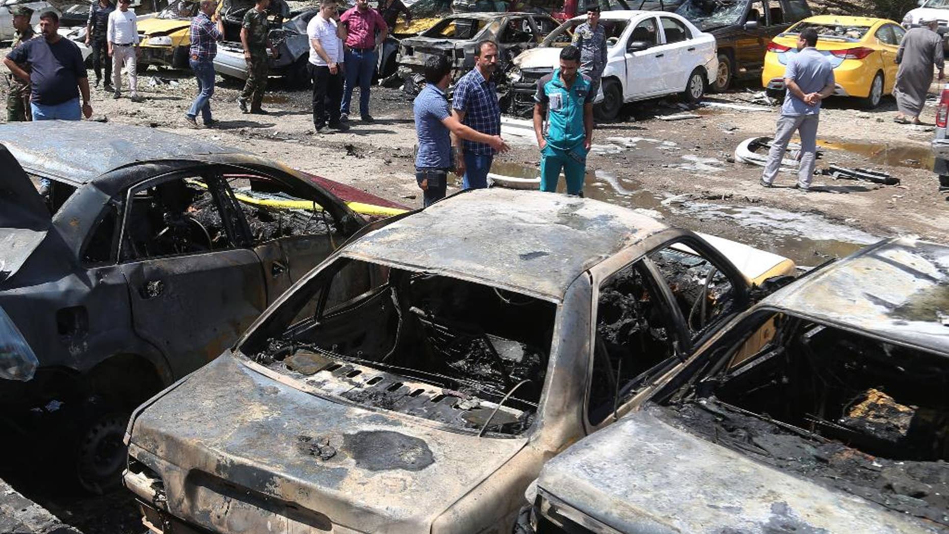 April 14, 2015: People and security forces gather at the scene of a car bomb explosion in a parking lot outside Yarmouk hospital in western Baghdad, Iraq. Car bombs went off Tuesday morning in and around the Iraqi capital, killing and wounding civilians, officials said.