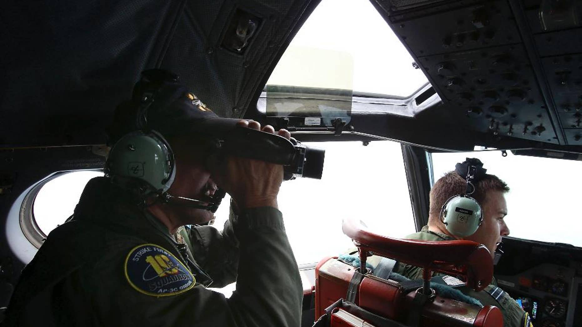 In this Wednesday, March 26, 2014 photo, Flight Engineer Ron Day on board a Royal Australian Air Force AP-3C Orion, seraches for the missing Malaysia Airlines Flight 370 in the southern Indian Ocean. A French satellite scanning the Indian Ocean for remnants of the missing jetliner found a possible plane debris field containing 122 objects, a top Malaysian official said Wednesday, calling it "the most credible lead that we have." (AP Photo/Paul Kane, Pool)