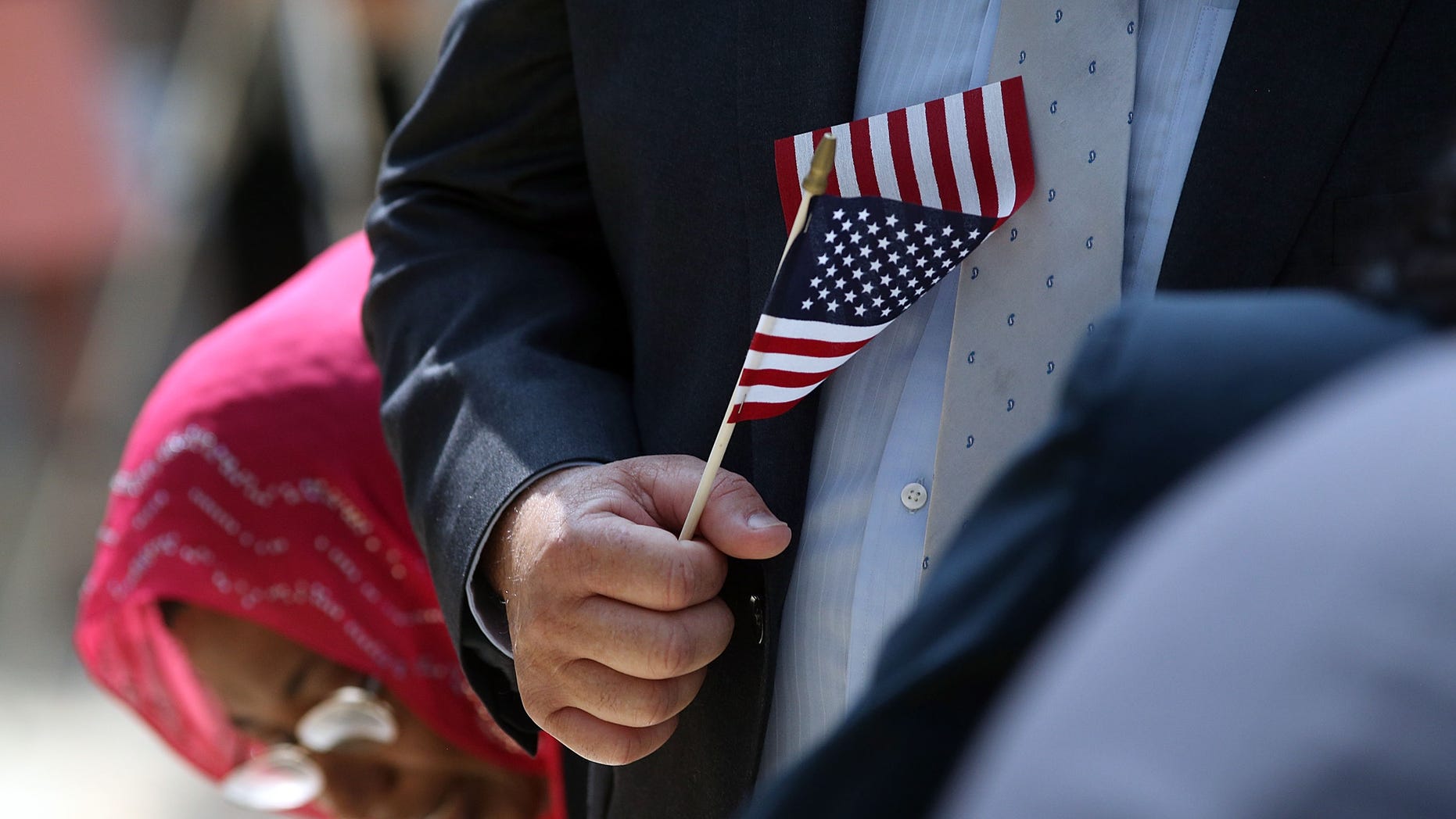 NEW YORK, NY - JULY 22: A man holds an American Flag before taking the Oath of Allegiance during a special naturalization ceremony at the Metropolitan Museum of Art on July 22, 2014 in New York City. Over fifty people representing countries from Albania to Burundi took part in the morning ceremony at the American Wing of the museum. The Oath of Allegiance was administered by U.S. Citizenship and Immigration Services (USCIS) Deputy Director Lori L. Scialabba. (Photo by Spencer Platt/Getty Images)