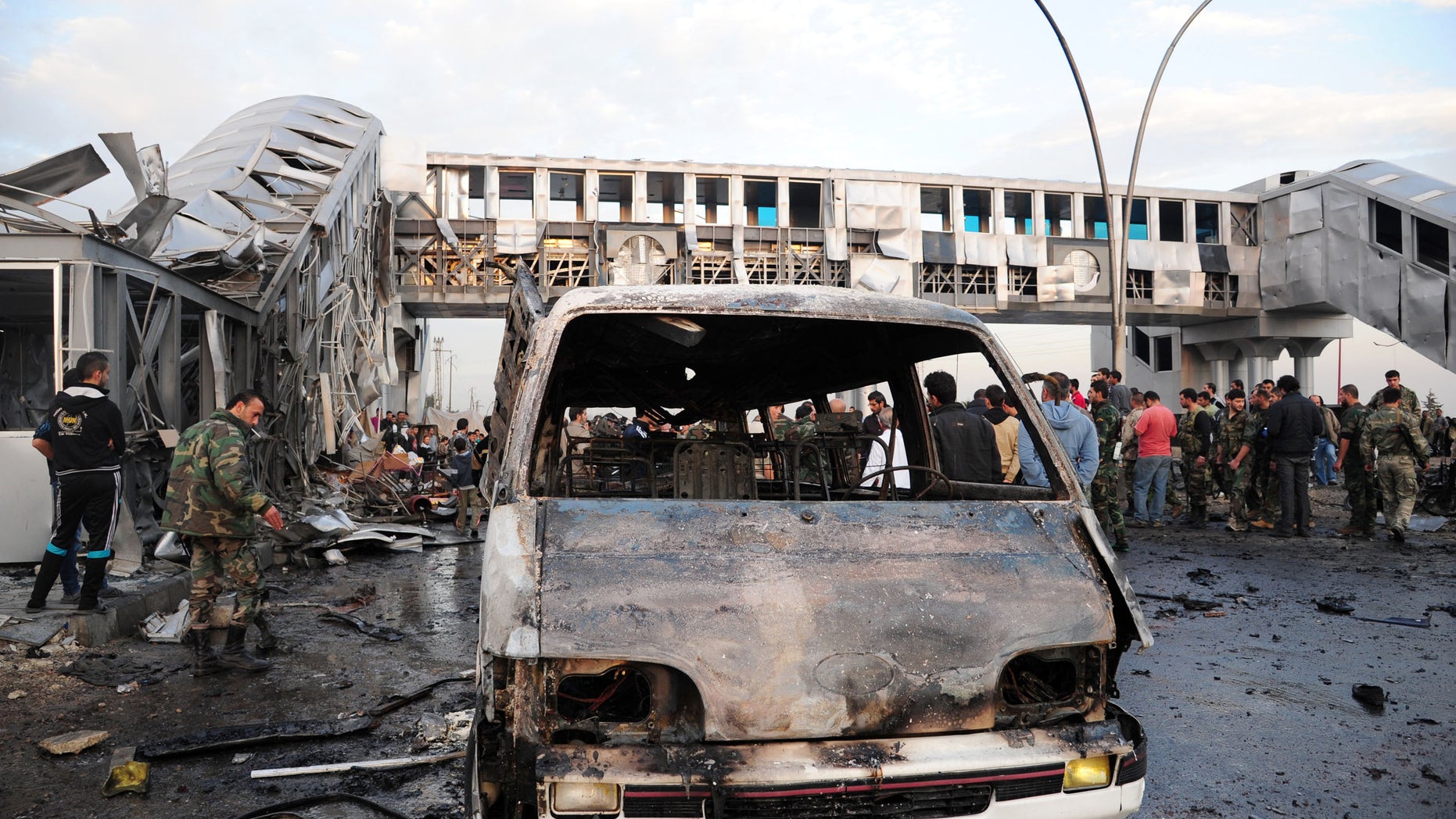 In this photo released by the Syrian official news agency SANA, Syrian government soldiers and citizens gather at a bus station which was attacked by a suicide car bomb, in the town of Sumariyah, southwest of Damascus, Syria, Tuesday Nov. 26, 2013. Several people were killed and wounded, Syrian state TV said. (AP Photo/SANA)
