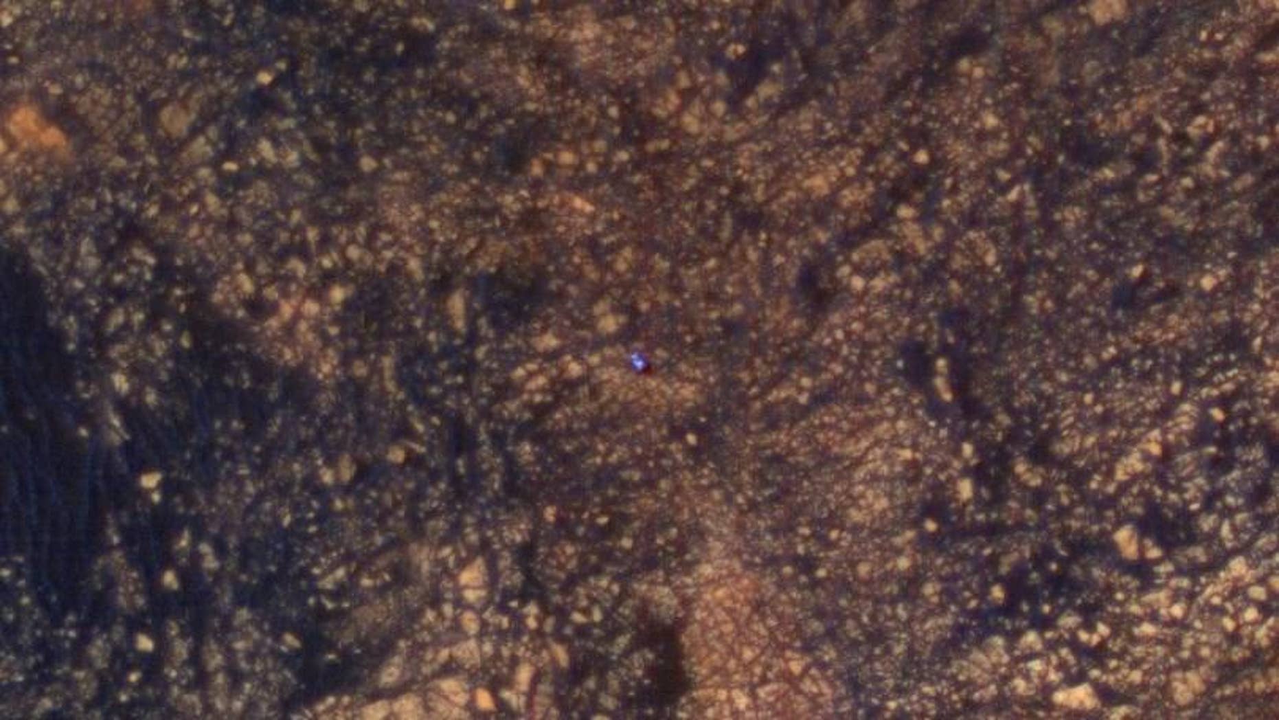 The feature that appears bright blue at the center of this scene is NASA's Curiosity Mars rover amid tan rocks and dark sand on Mount Sharp, as viewed by the HiRISE camera on NASA's Mars Reconnaissance Orbiter on June 5, 2017. The rover is about 10 feet long and not really as blue as it looks here. (Credits: NASA/JPL-Caltech/Univ. of Arizona)