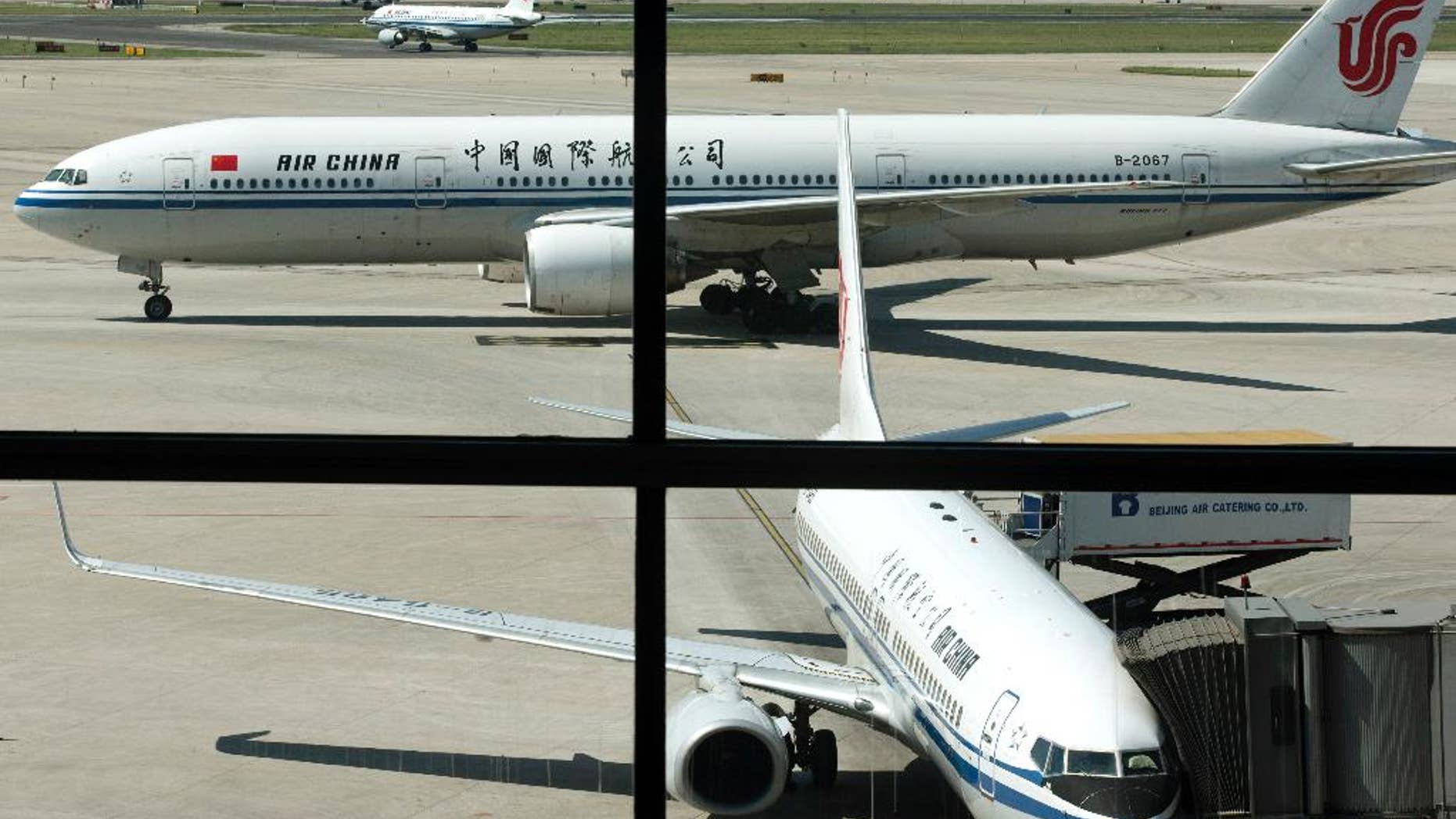 FILE - In this Sept. 5, 2013 file photo, an Air China's Boeing 777 jet, top, taxis to a gate after landing at Beijing International Airport in Beijing, China. Air China said Thursday, Sept. 8, 2016, that it had removed copies of its inflight magazine containing an article telling visitors to take precautions when visiting areas of London with large ethnic-minority populations. The state-owned airline, China's flag carrier, said in an e-mail to The Associated Press that the September issue of "Wings of China" used "inappropriate" language and that the article didn't represent the airline's views. (AP Photo/Alexander F. Yuan, File)