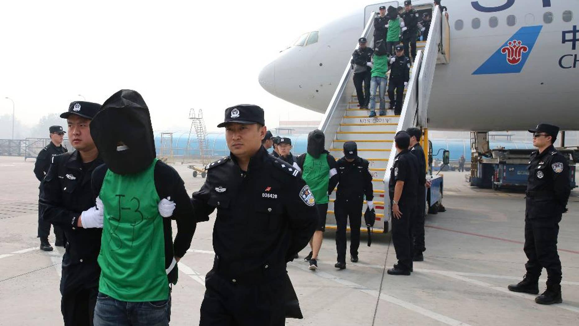 FILE - In this April 13, 2016 file photo released by Xinhua News Agency, Chinese suspects involved in wire fraud are escorted off a plane upon arriving at the Beijing Capital International Airport in Beijing, China. Taiwanese officials have protested Malaysia's deportation of 32 of the self-ruled island's nationals to China to face wire fraud charges. The deportation follows the sending of nearly four dozen Taiwanese from Kenya to China last month, a case that has raised concerns Beijing is exerting diplomatic pressure over the island it considers its own territory. The Taiwanese Cabinet, in a statement late Saturday, April 30, says China pressured Malaysia to deport the Taiwanese wire fraud suspects to the mainland. (Yin Gang/Xinhua News Agency via AP, File) NO SALES