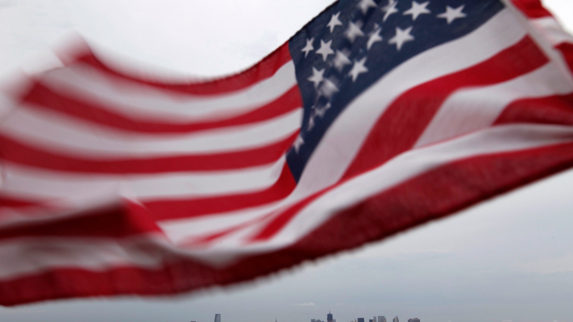 A U.S. flag flutters over top of the skyline of New York (R) and Jersey City (L), as seen from Bayonne, New Jersey, August 6, 2011. New York will mark the 10th anniversary of the attack on the World Trade Center with ceremonies on September 11. REUTERS/Gary Hershorn (UNITED STATES - Tags: CITYSCAPE DISASTER IMAGES OF THE DAY)