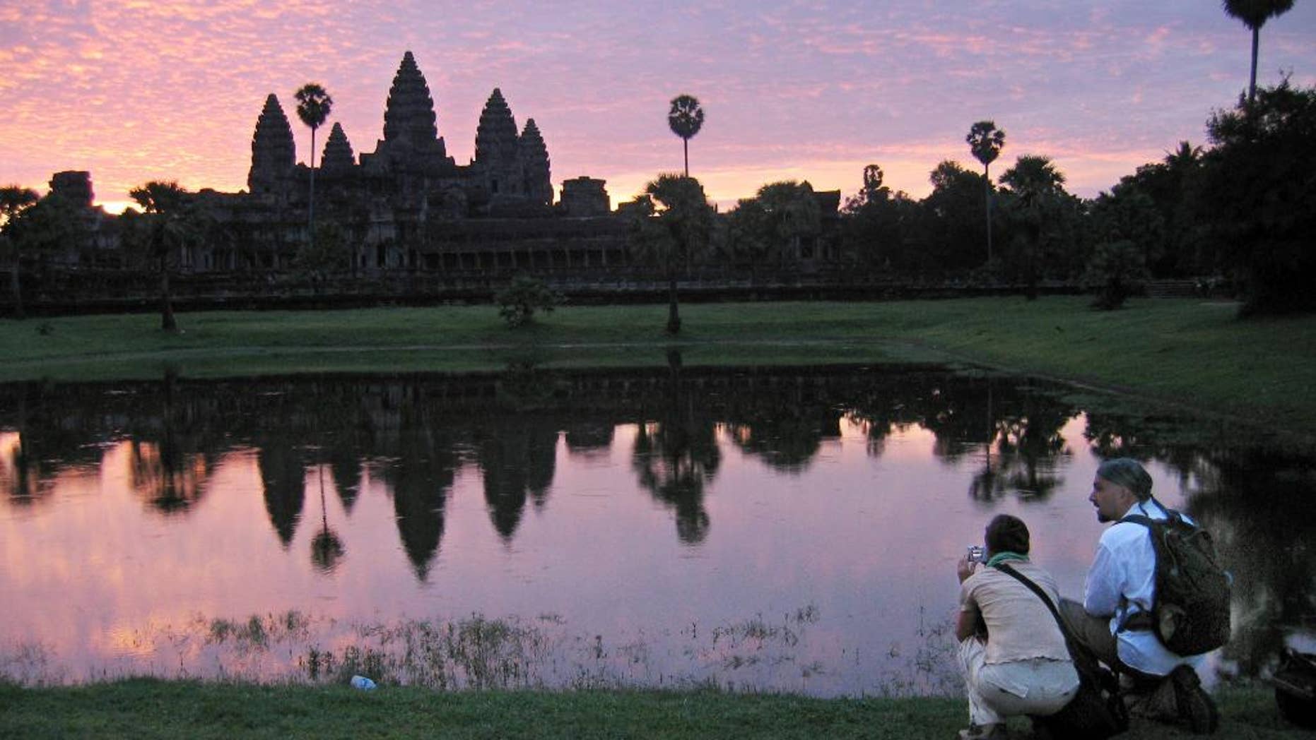 FILE - In this July 14, 2014 file photo, tourists look at the view of the Angkor Wat temples at sunrise, outside Siem Reap, Cambodia. An Australian archeologist says he and colleagues have found evidence of previously undiscovered medieval urban and agricultural networks surrounding the ancient city of Angkor Wat. Using high-tech lasers to scan the Cambodian jungle, Damian Evans and colleagues say they found traces of extensive networks surrounding the monumental stone temple complex at Angkor Wat. (AP Photo/Anat Givon, File)