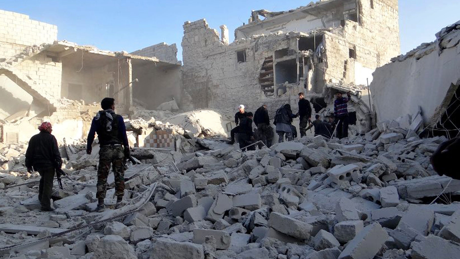 Citizen journalism image provided by Aleppo Media Center AMC which has been authenticated based on its contents and other AP reporting, shows Syrian rebels stand in the rubble of damaged buildings due to government airstrikes, in the neighborhood of Karam Tarab near Aleppo International Airport, in Aleppo, Syria, Wednesday, Feb. 13, 2013. Syrian rebels fought pitched battles Wednesday against regime forces at a military base that protects a major airport in the country's north in fighting that has left more than 40 government troops dead, opposition activists said. (AP Photo/Aleppo Media Center AMC)