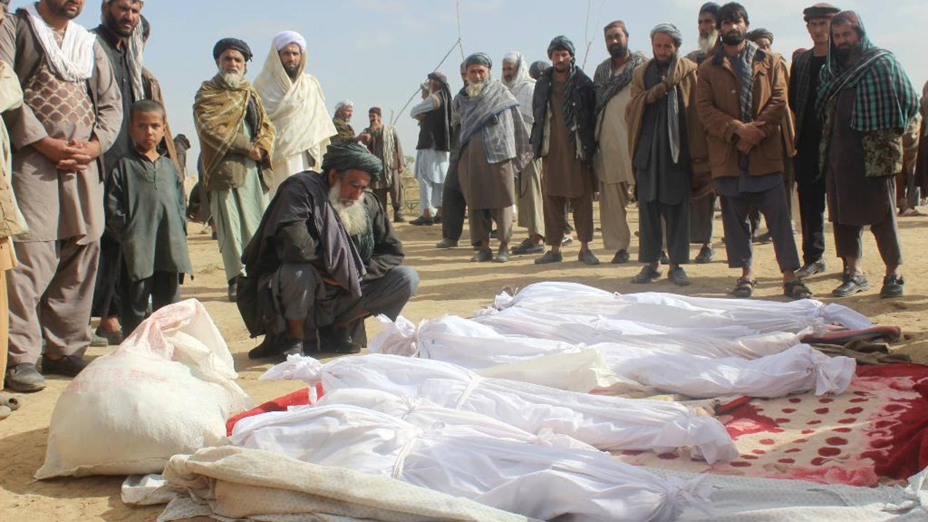 FILE -- In this Nov. 4, 2016 file photo, Afghan villagers gather around several victims' bodies who were killed during clashes between Taliban and Afghan security forces in the Taliban-controlled, Buz-e Kandahari village in Kunduz province, Afghanistan. In a statement released Thursday, Jan. 12, 2017, the U.S. military in Afghanistan said the results of its investigation into the November firefight with the Taliban in Kunduz province show that American troops had fired on Afghan homes, killing 33 civilians. (AP Photo/Najim Rahim, File)