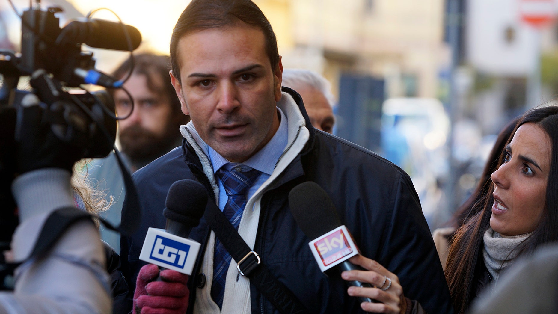 Costa Concordia official Ciro Ambrosio receives media attention as he arrives at the Grosseto court, Italy, where the trial for the crash of the Concordia liner, which struck a reef as it sailed close to the Giglio island, causing the death of thirty people, is under way Tuesday, Dec. 17, 2013. Ciro Ambrosio, who was serving as First Officer on Jan. 13, 2012 during the crash, told a court in Tuscany Tuesday he had to communicate with hand gestures with Captain Francesco Schettino because the commander was chatting on the phone. Ambrosio said he was off-duty but took the helm and gave orders to the helmsman because Schettino was "distracted" by the phone conversation. (AP Photo/Alessandro La Rocca, Lapresse) ITALY OUT