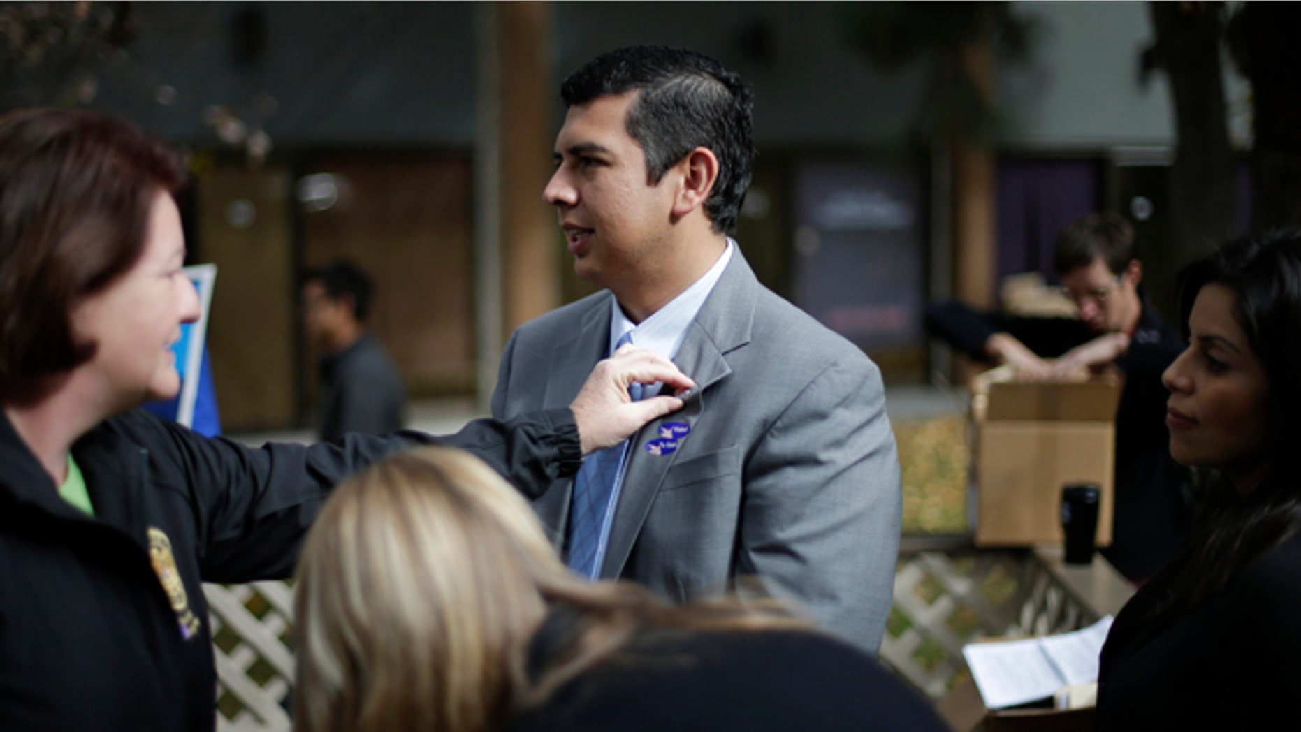 David Alvarez, center, a San Diego city councilman and Democratic candidate for mayor, stands while California Assembly Majority Leader Toni Atkins, left, adjusts a pin on his lapel as he meets with supporters Tuesday, Nov. 19, 2013, in San Diego. San Diegans head to the polls today to choose a new mayor, after Bob Filner's resignation amid allegations of sexual harassment has left the city with an interim mayor. (AP Photo/Gregory Bull)