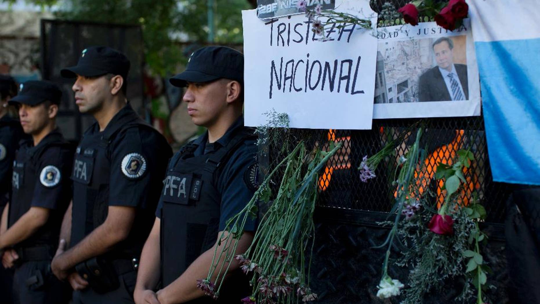 An image of the late prosecutor Alberto Nisman is taped to a grate next to a hand written sign that reads in Spanish; "National sadness," outside the funeral home where a private wake was held before the start of the funeral procession, in Buenos Aires, Argentina, Thursday, Jan. 29, 2015. The prosecutor was scheduled to appear before Congress the day after he was found dead in his apartment on Jan. 18, to detail his allegations that President Cristina Fernandez had conspired to protect some of the Iranian suspects in the 1994 bombing of a Jewish center. The man who gave Nisman the gun that killed him said Wednesday that Nisman feared for the safety of his daughters and didn't trust the policemen protecting him. (AP Photo/Rodrigo Abd)