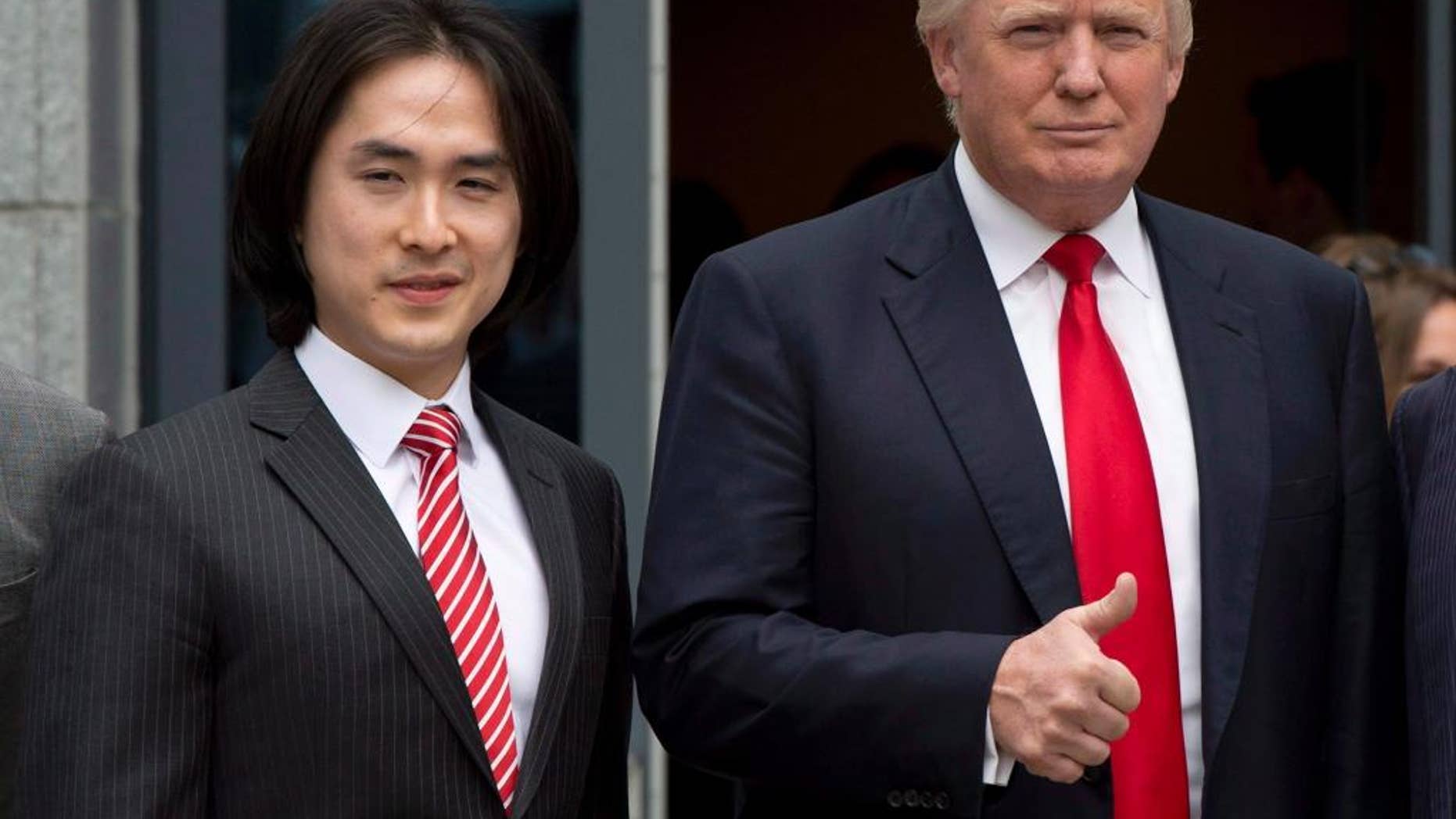 FILE - In this June 19, 2013, file photo, Donald Trump gives a thumbs-up as he poses with Tiah Joo Kim, left, CEO and president of Holborn Group, upon arrival to announce the building of Trump International Hotel and Tower Vancouver in downtown Vancouver, Canada. Malaysian property developer Tiah got way more than he bargained for when he signed a licensing deal to use the Trump brand on the Trump International Hotel and Tower that he is opening on Tuesday, Feb. 28, 2017 in Vancouver. (Jonathan Hayward/The Canadian Press via AP)