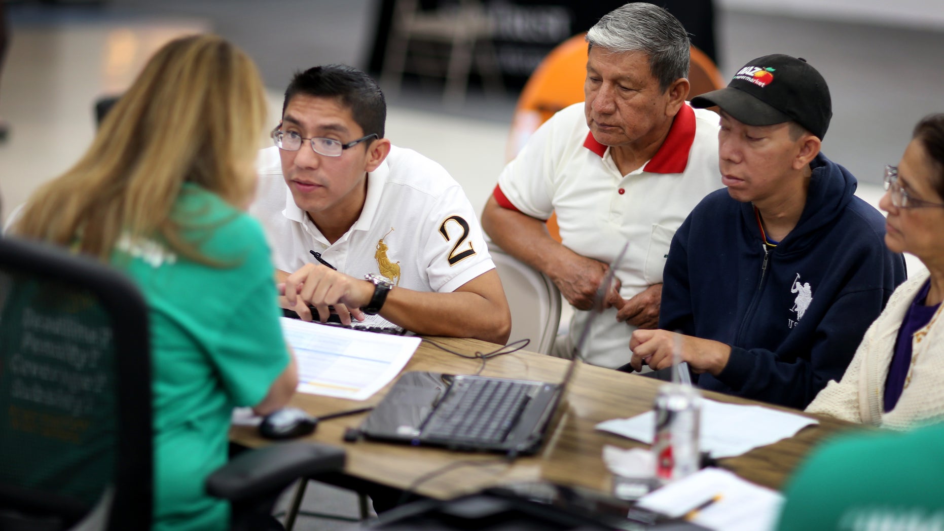 MIAMI, FL - MARCH 20: Paul Paucar (L-R), Homero Paucar, Giovanny Paucar and Ivonne Cucalon sit with, Jessica Adames, an insurance agent from Sunshine Life and Health Advisors as they try to purchase health insurance under the Affordable Care Act at a store setup in the Mall of Americas on March 20, 2014 in Miami, Florida. The owner of Sunshine Life and Health Advisors, Odalys Arevalo, said she has seen a surge in people, some waiting up to 3 hours or more in line, trying to sign up for the Affordable Care Act before the open enrollment period for individual insurance ends on March 31. (Photo by Joe Raedle/Getty Images)