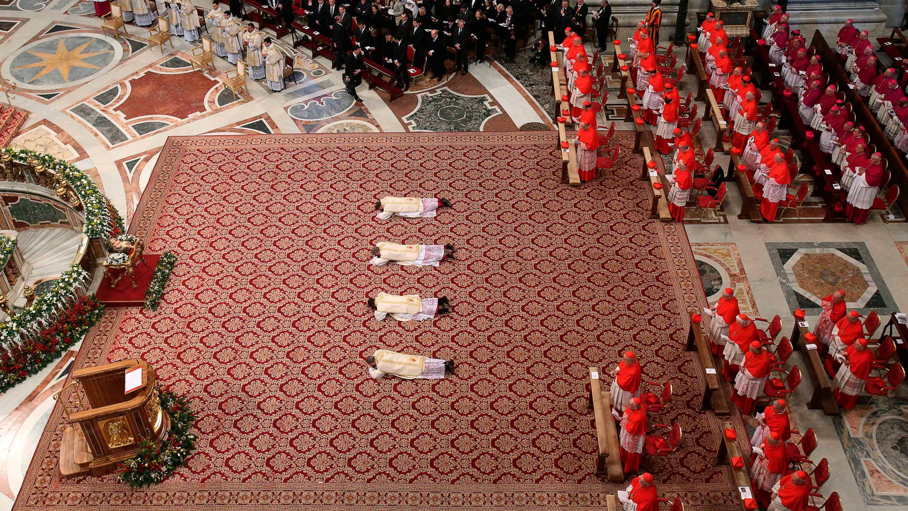From left to right, Angelo Vincenzo Tani, of Italy, Fortunatus Nwachukwu, of Nigeria, Georg Ganswein, of Germany, and Nicolas Marie Denis Thevenin lie on the ground as they are named bishops during an Epiphany mass celebrated by Pope Benedict XVI in St.Peter's Basilica at the Vatican, Sunday, Jan. 6, 2013. The Epiphany day, is a joyous day for Catholics in which they recall the journey of the Three Kings or Magi to pay homage to Baby Jesus. (AP Photo/Alessandro Di Meo, Pool)
