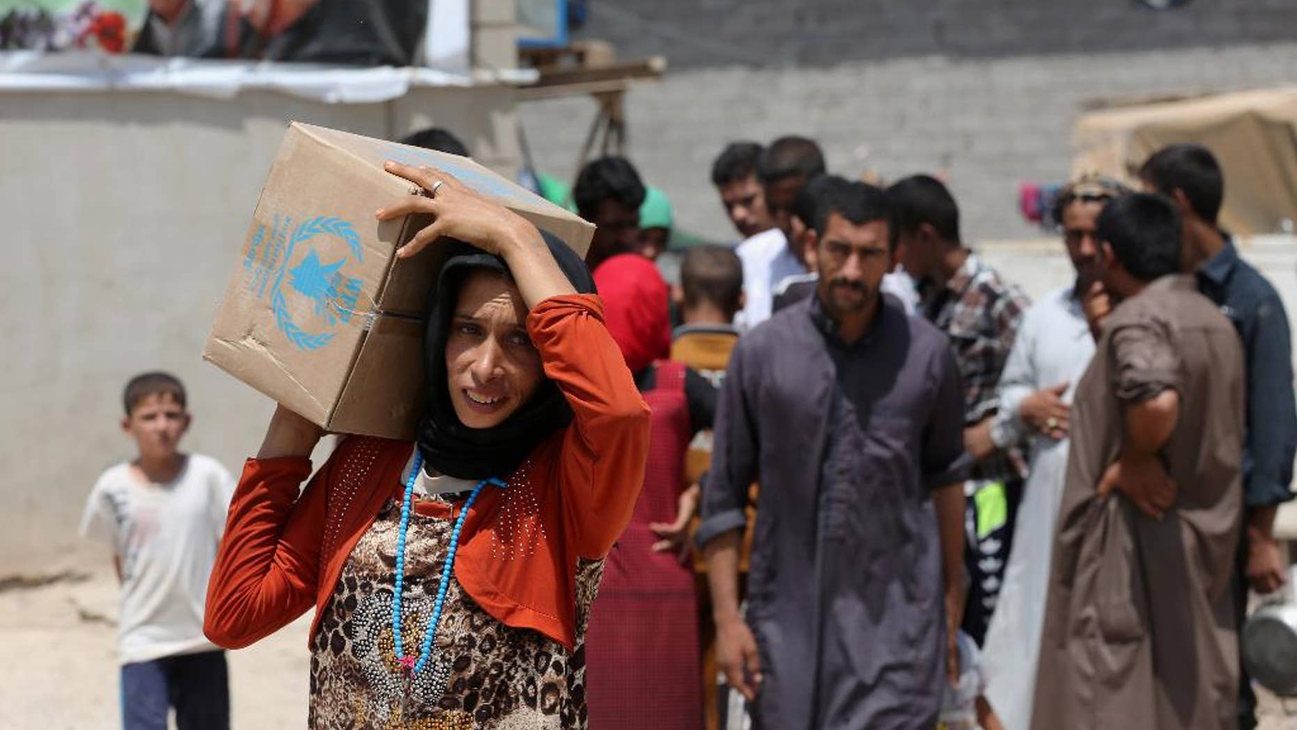 A woman carries a box of food from the World Food Programme at al-Takia refugee camp in Baghdad, Iraq, Thursday, July 30, 2015. The number of people displaced within Iraq due to violence and fighting by the Islamic State group has exceeded 3 million, the United Nations said in June. (AP Photo/Khalid Mohammed)