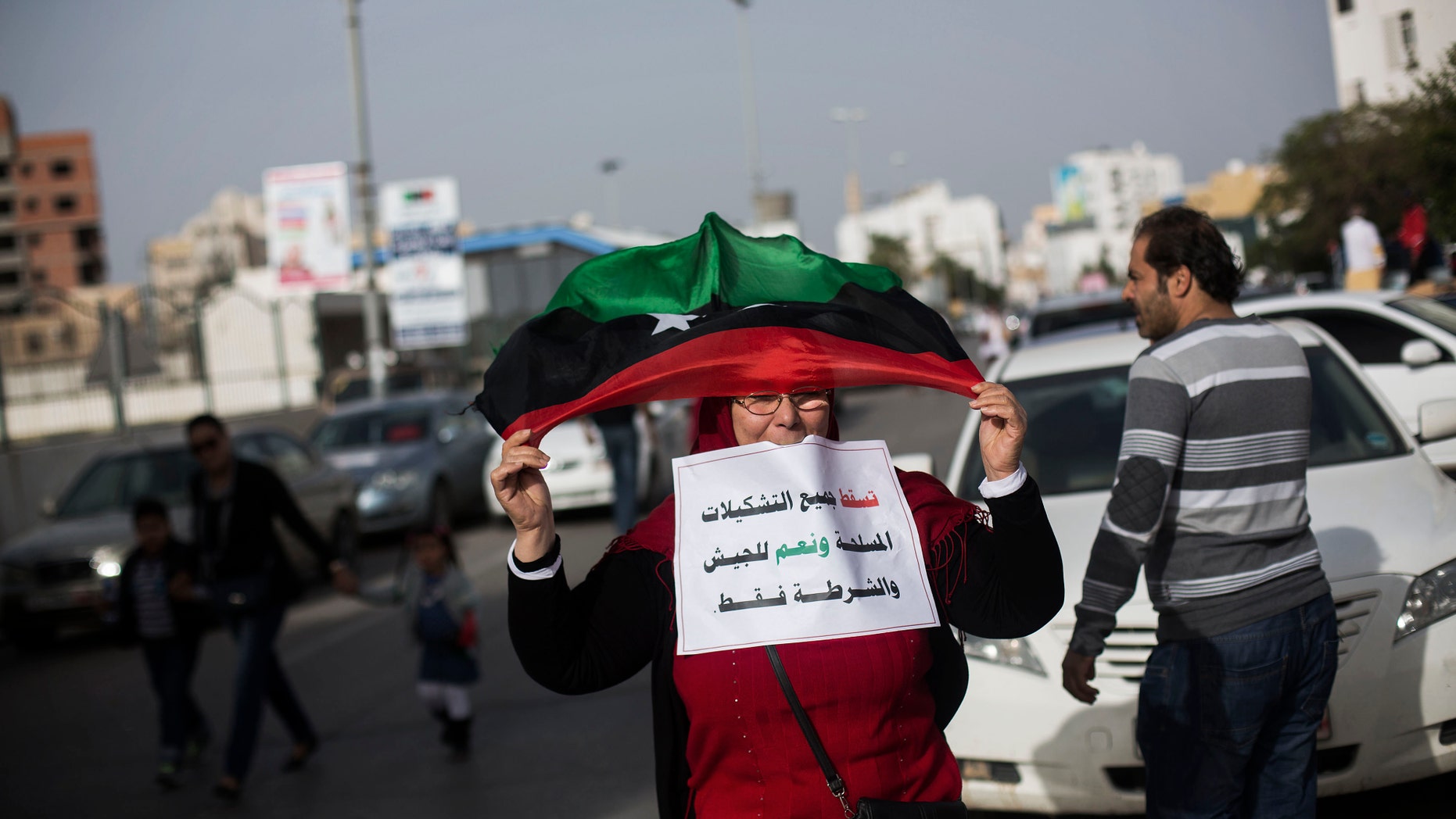 Nov. 22, 2013: A Libyan woman waves a Libyan flag to support the new national army and the police corps during a protest in Tripoli, Libya. Thousands of protesters have gathered in Libya's capital to call on unlawful armed groups to leave the city, a week after militiamen killed more than 40 people. The head of Tripoli's local council, Al-Sadat al-Badri, told the crowd on Friday that the city will remain on strike until the capital and its surroundings are free of militias. The Arabic reads, "Down all the armed group. Yes to the army and the police only."