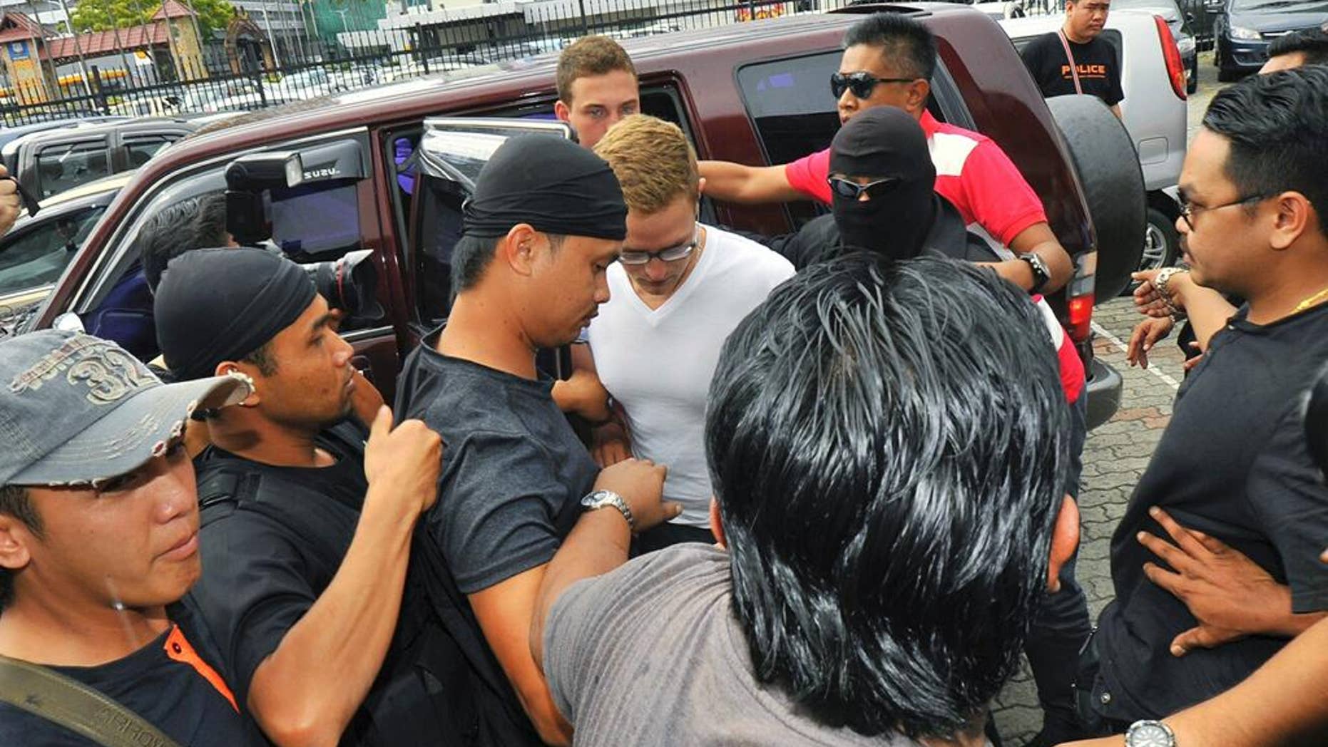 Dutch national Dylan Snel, in white shirt, center, is escorted by police as he arrives at court in Kota Kinabalu, in eastern Sabah state on Borneo island, Malaysia, Friday, June 12, 2015. Snel was among 10 people who stripped naked and took photos on Mount Kinabalu on May 30. A local official has said the foreigners’ behavior caused an earthquake near the mountain last Friday that killed 18 climbers. (AP Photo/Syaradik Babuca)