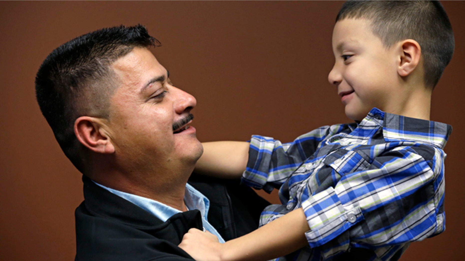 In this photo taken Friday, Oct. 17, 2014, Ignacio Lanuza-Torres holds his son, Isaiah, 4, as he has his photo taken in Seattle. A U.S. Immigration and Customs Enforcement attorney forged a document in an attempt to deport Lanuza-Torres, an immigrant seeking to stay in the country with his wife and children, according to a new lawsuit. The lawsuit, filed Thursday, Oct. 23, 2014, in a Seattle U.S. District Court, seeks $500,000 in damages for Ignacio Lanuza-Torres because the forgery cost him years of courtroom battles and uncertainty over his future. (AP Photo/Elaine Thompson)