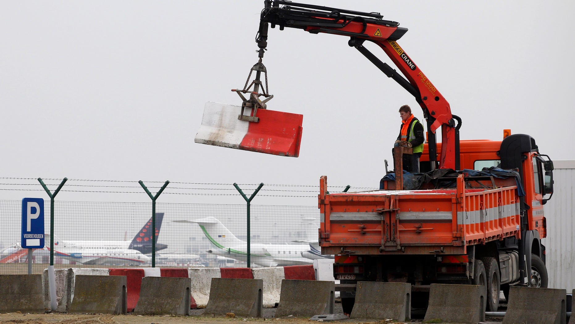 Workers place concrete blocks to block access to a security fence next to the tarmac, at Brussels international airport, Tuesday, Feb. 19, 2013. Eight masked gunmen made a hole in a security fence at Brussels' international airport, drove onto the tarmac and snatched some $50 million worth of diamonds from the hold of a Swiss-bound plane without firing a shot, authorities said Tuesday. (AP Photo/Yves Logghe)